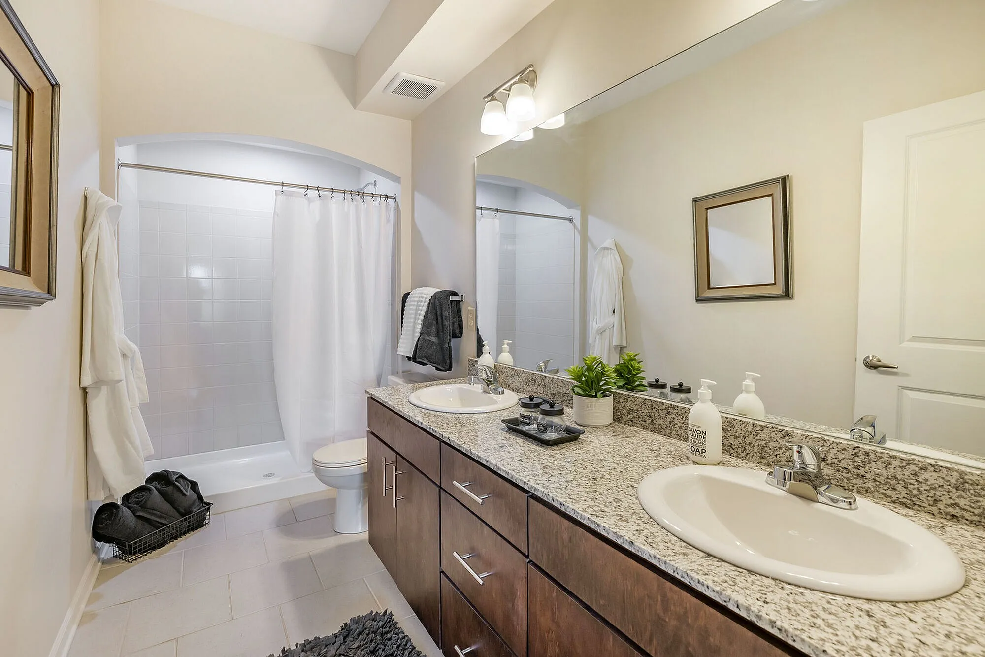 Elegant bathroom with granite countertops, dual sinks, and a spacious shower, featuring a modern design and luxurious amenities.