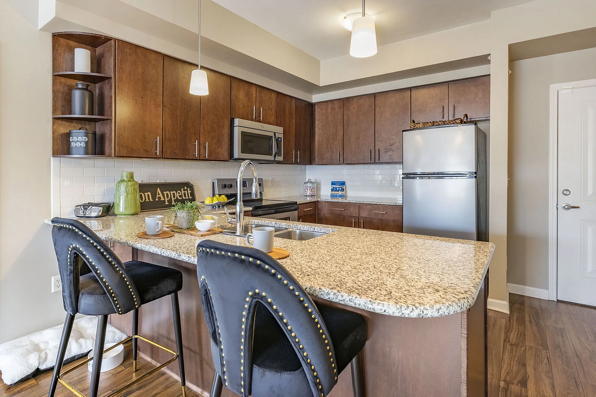 Modern kitchen with elegant granite countertops, stylish bar stools, and stainless steel appliances, creating a warm and inviting atmosphere.
