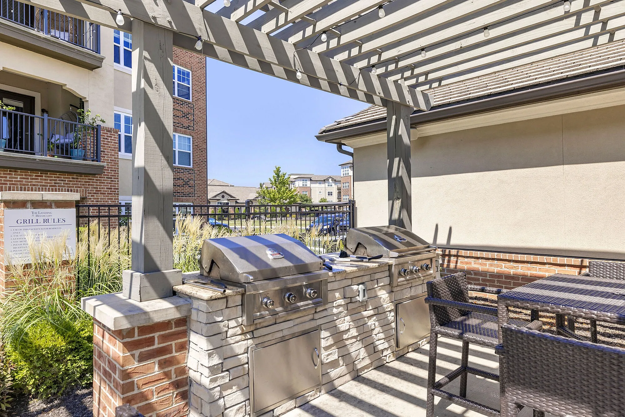 Chic outdoor space featuring modern stainless steel grills under a stylish pergola, perfect for entertaining and enjoying sunny days.
