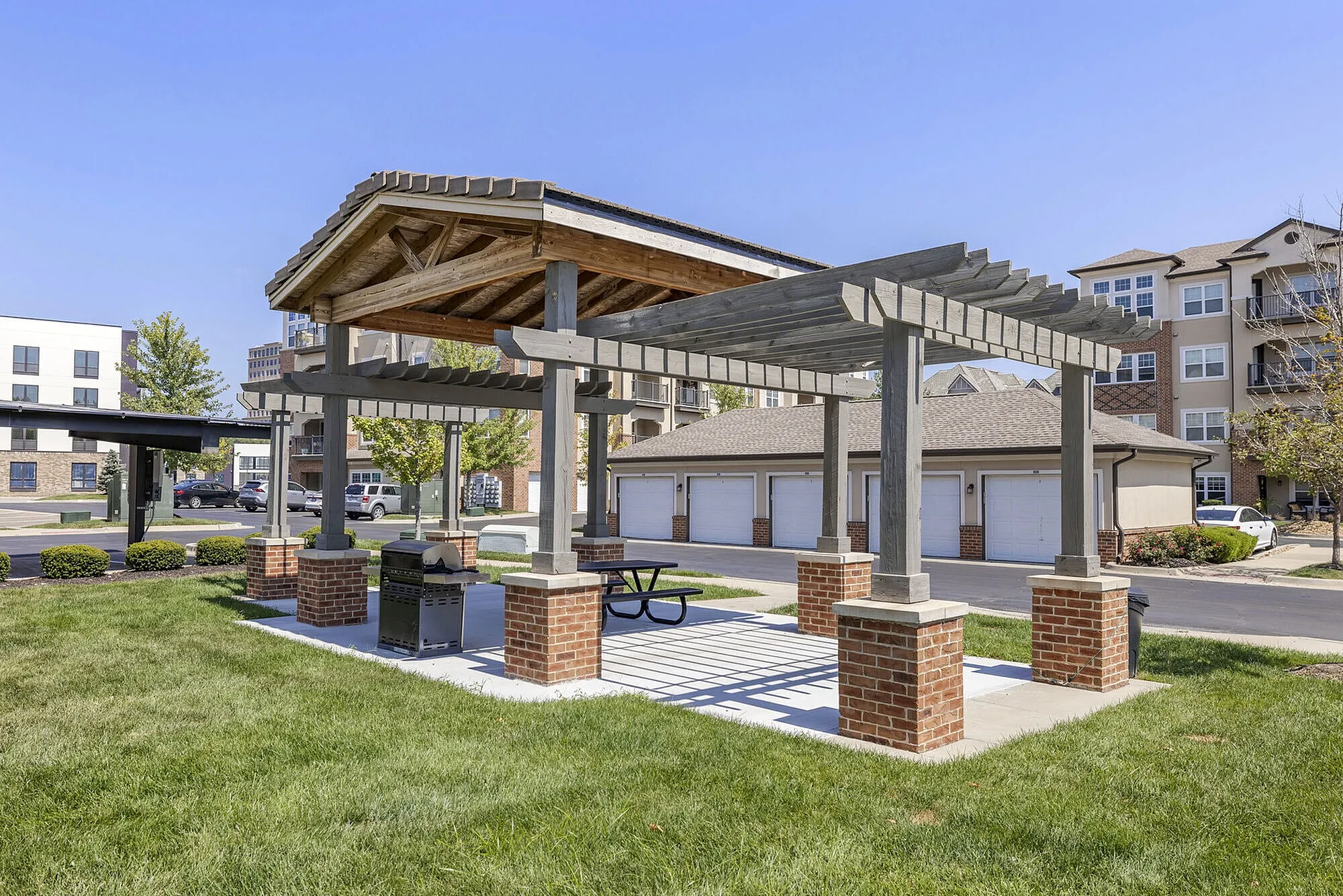 Charming outdoor pavilion with a modern pergola and picnic table, ideal for gatherings, located in a scenic apartment community.