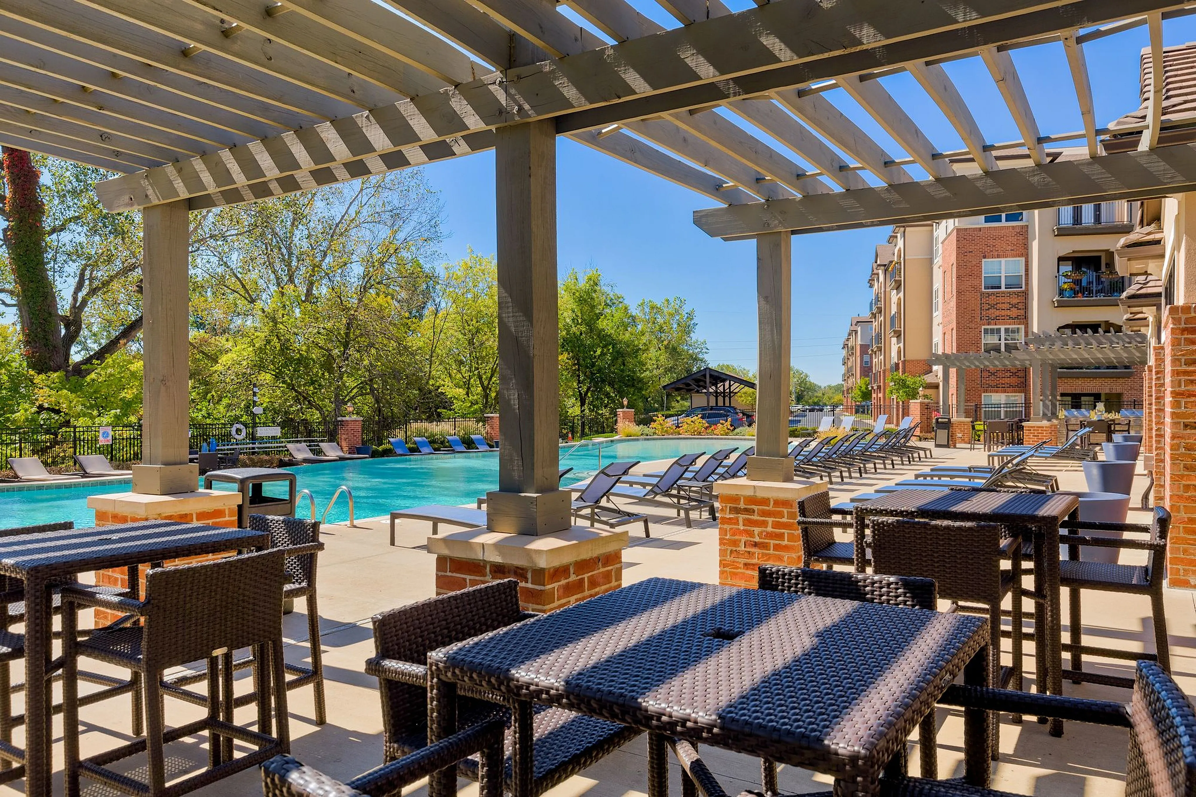 Elegant outdoor patio showcasing a luxurious swimming pool with sun loungers and lush greenery, perfect for relaxation and leisure.