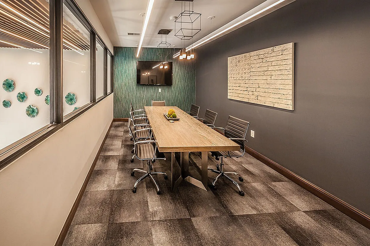 Elegant conference room with modern design, featuring a long wooden table surrounded by sleek office chairs and ambient lighting.