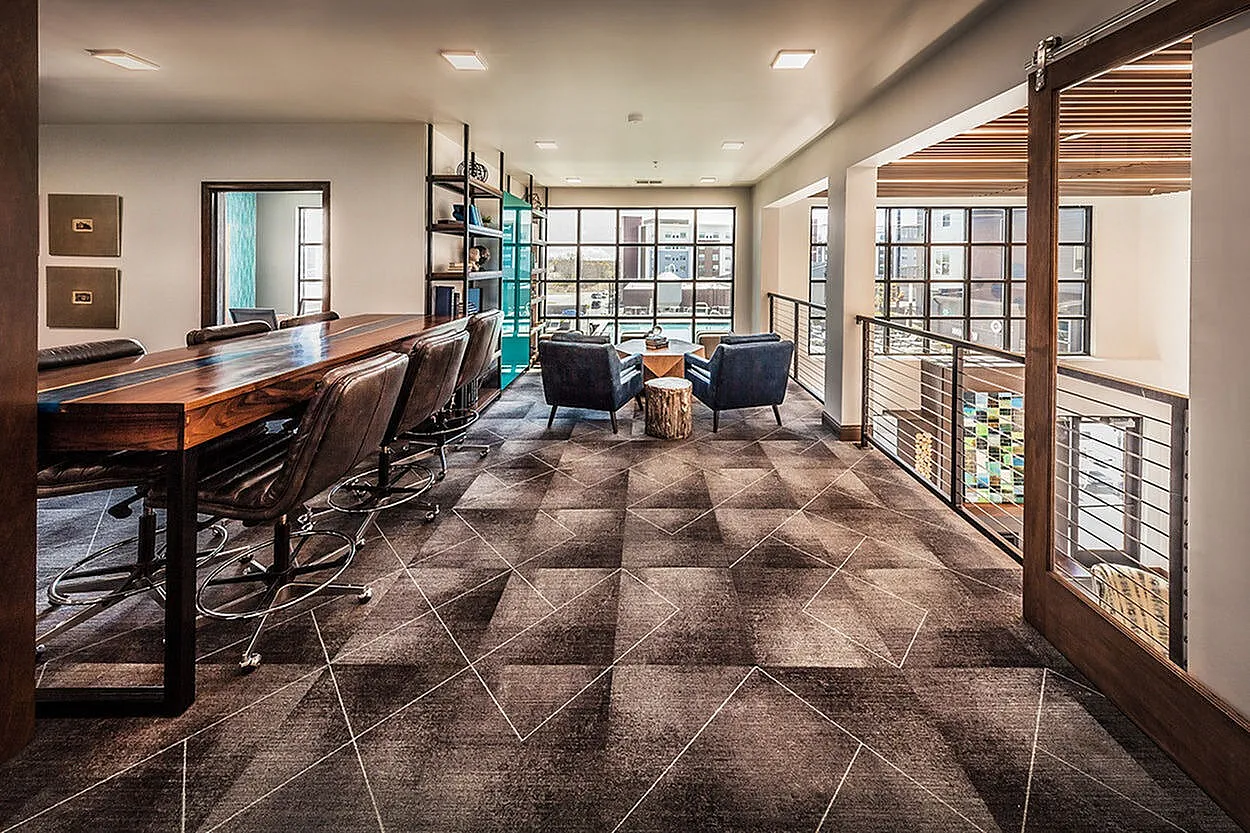 Modern lounge area with sleek leather seating, expansive windows, and a stylish geometric carpet design, perfect for relaxation or meetings.