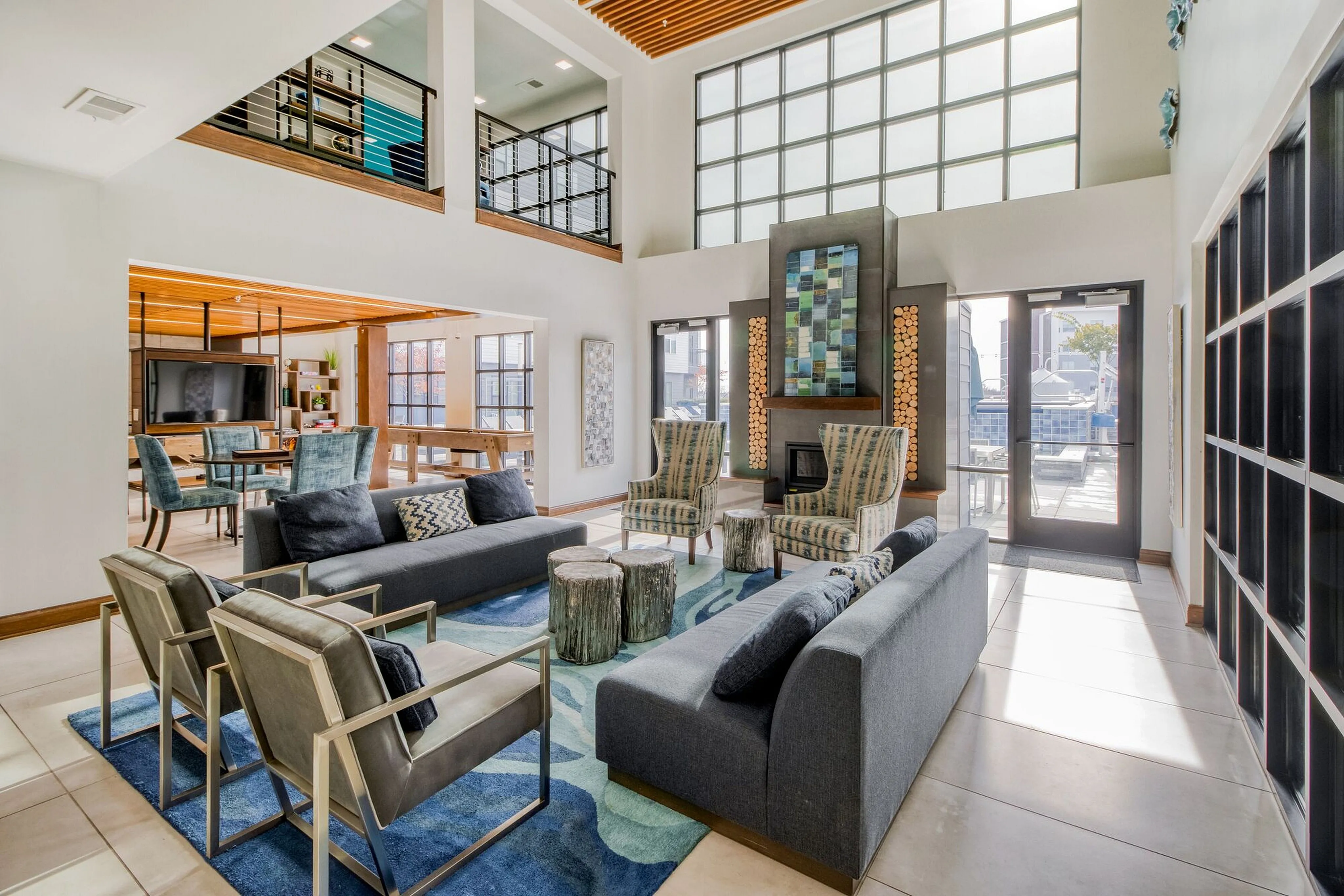 Spacious and modern living area with high ceilings, chic seating, large windows, and a vibrant fireplace, perfect for stylish gatherings.