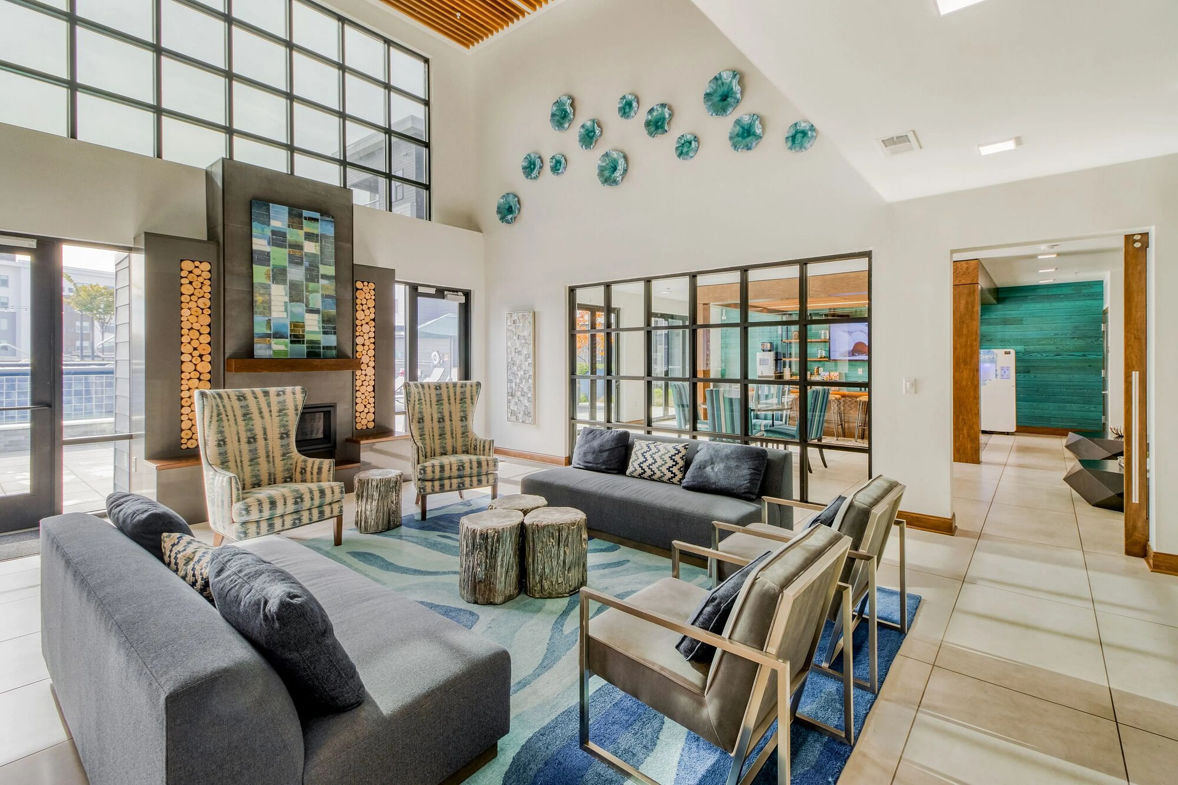 Bright and modern living area featuring large windows, chic lounge seating, and contemporary artwork in a spacious open layout.