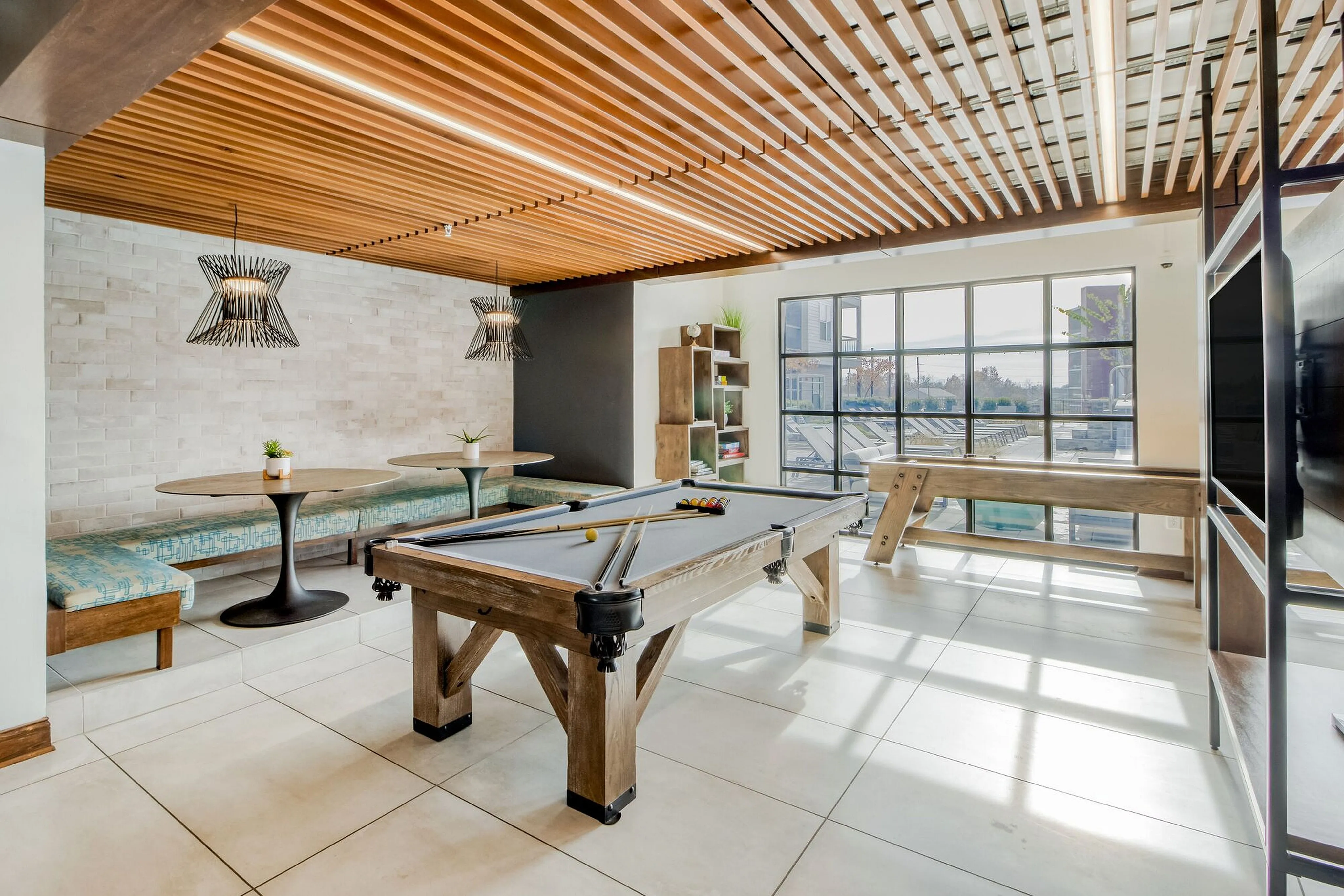 Chic recreational space with modern pool table, cozy seating area, and floor-to-ceiling windows providing abundant natural light.