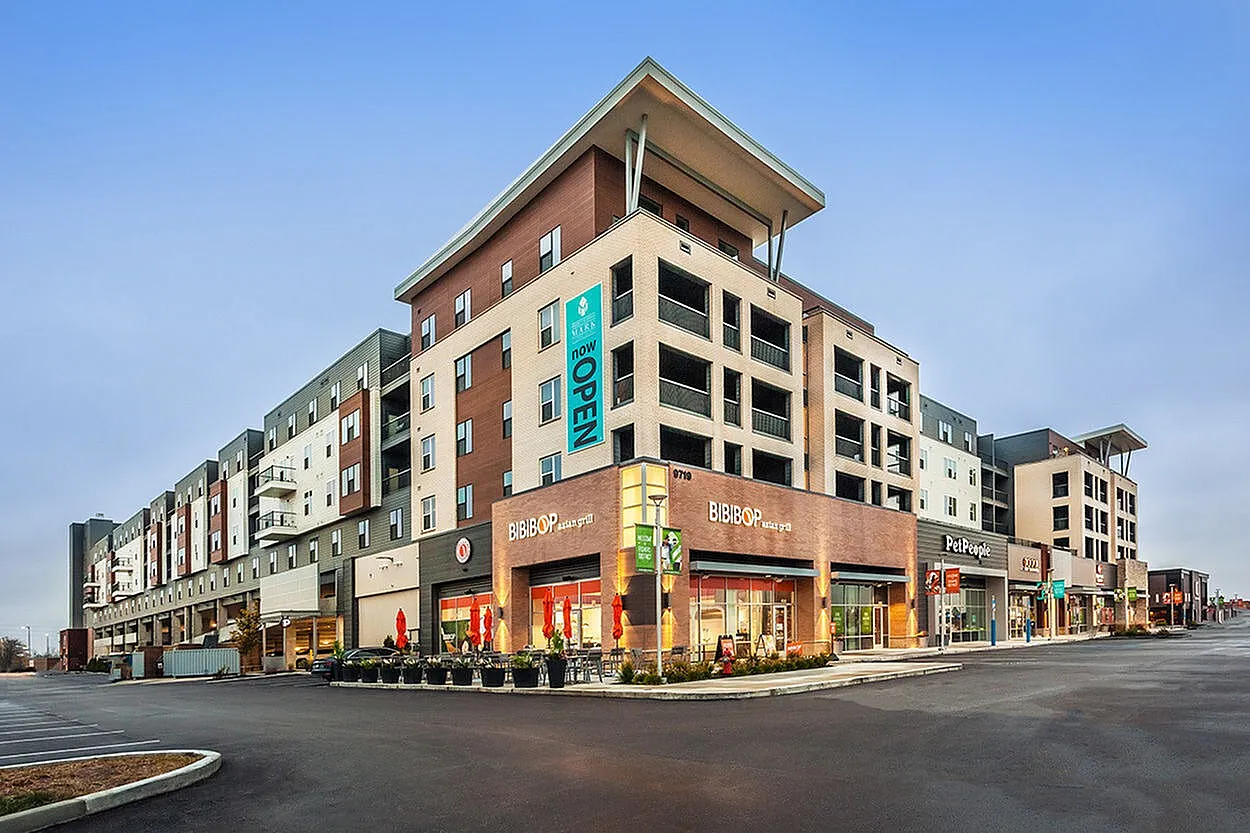 Modern mixed-use building with stylish retail stores and chic apartments above, located in a vibrant urban setting.