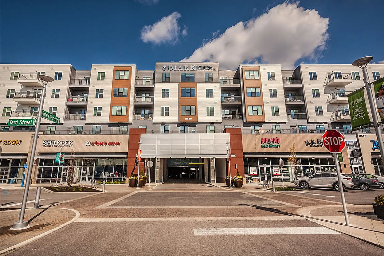 Modern apartment complex with retail storefronts below, under a clear blue sky, offering urban convenience and stylish living.