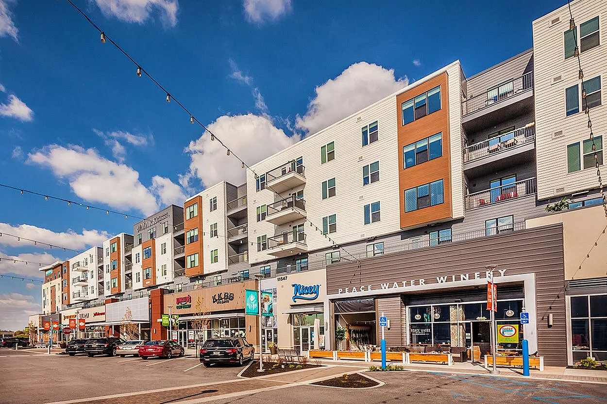 Modern apartment complex with vibrant retail spaces and chic balconies under a clear blue sky.