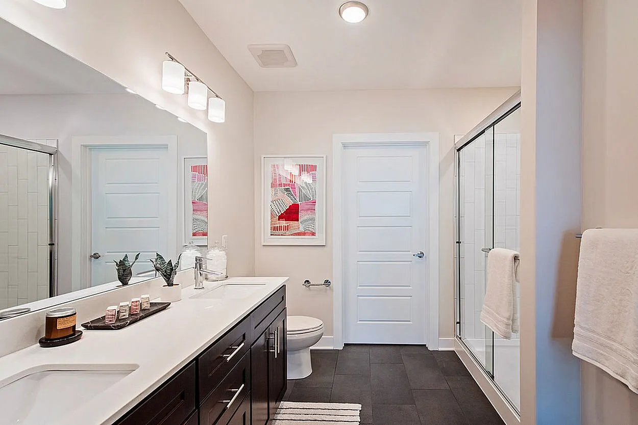 Modern bathroom with sleek fixtures, elegant dark wood vanity, and stylish decorative accents.