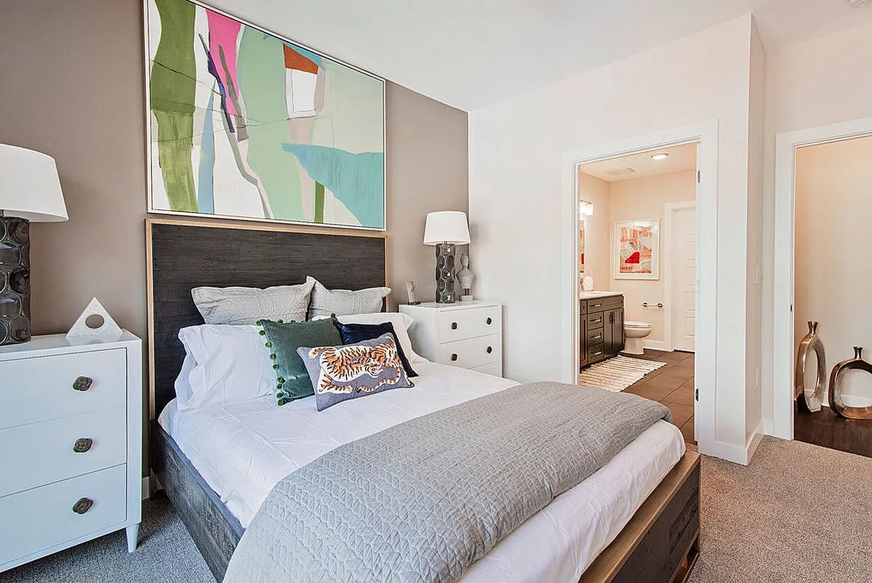 Contemporary bedroom with stylish decor, featuring a cozy bed, abstract artwork, and adjacent ensuite bathroom with modern fixtures.