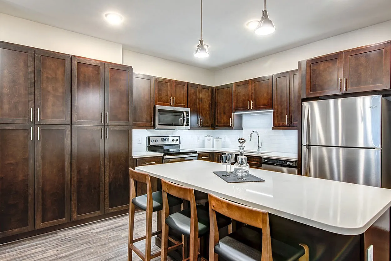 Modern kitchen with sleek stainless steel appliances, rich wooden cabinetry, and an elegant island with seating.