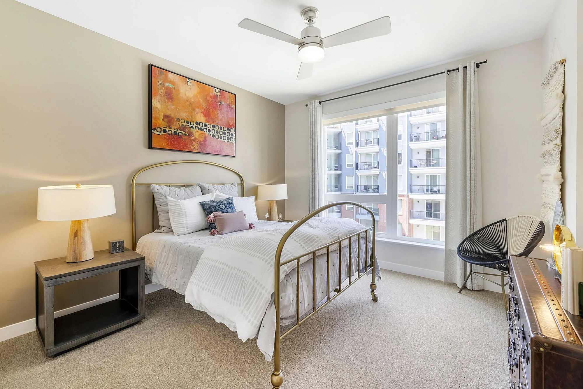 Bright, elegant bedroom with a modern metal bed frame, large window, and stylish decor creating a cozy ambiance.