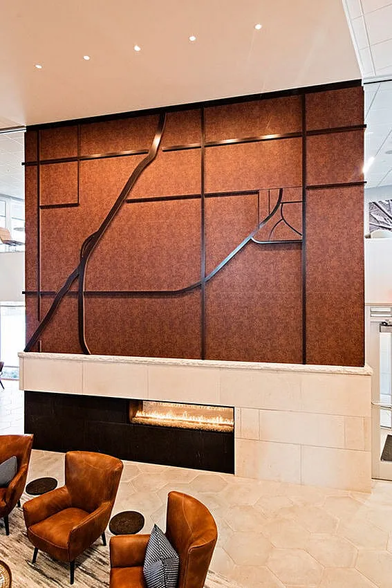 Luxurious lobby with elegant wood panel wall art and cozy modern seating by a sleek linear fireplace.