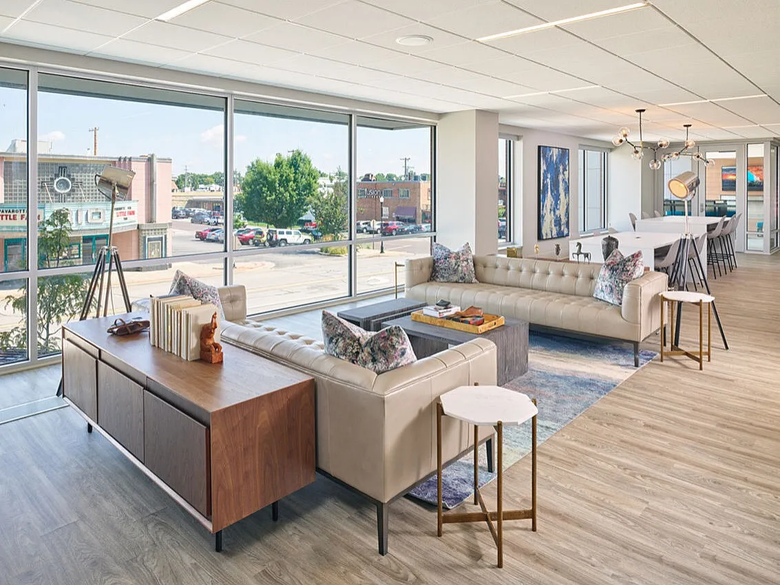 Bright and modern open-concept living area with chic leather sofas, floor-to-ceiling windows, and stylish decor, perfect for relaxation and entertaining.
