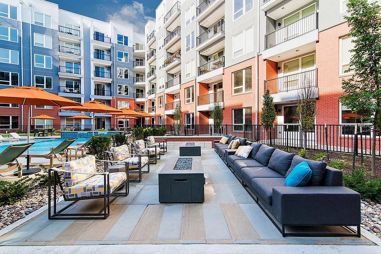 Modern apartment complex with vibrant outdoor seating area, sleek fire pit, and inviting pool, perfect for relaxation and entertaining.
