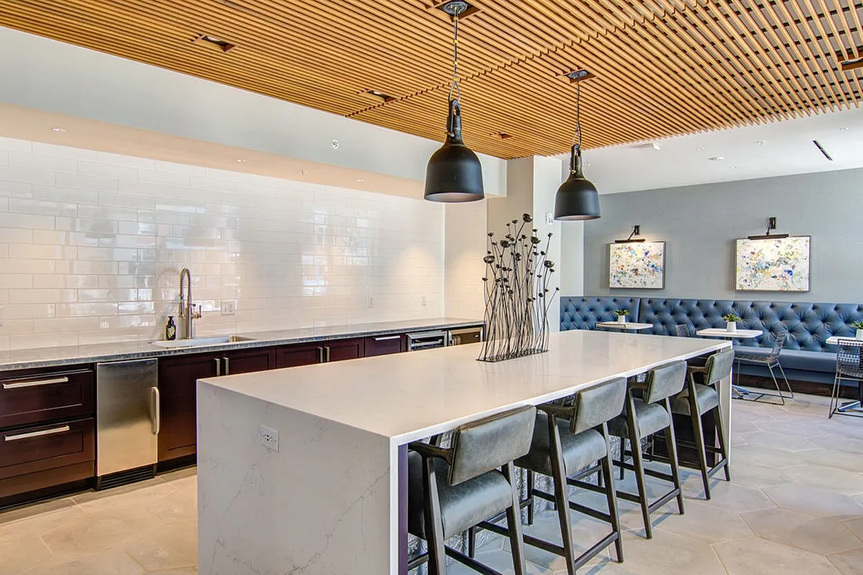 Modern kitchen and dining area with sleek marble island, plush seating, and contemporary lighting.