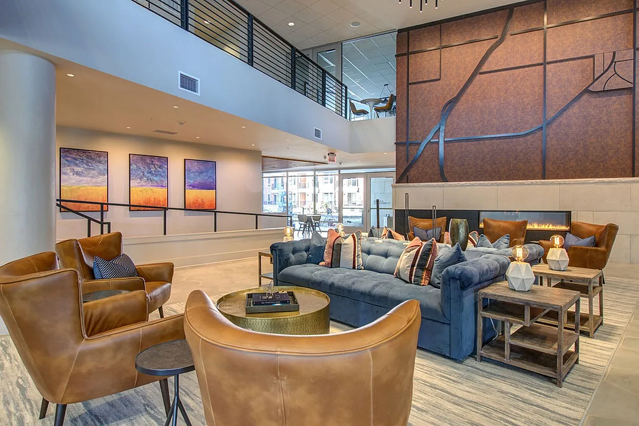 Luxurious modern lounge area with elegant leather chairs, plush blue sofa, glamorous artwork, and a cozy fireplace for ultimate relaxation.