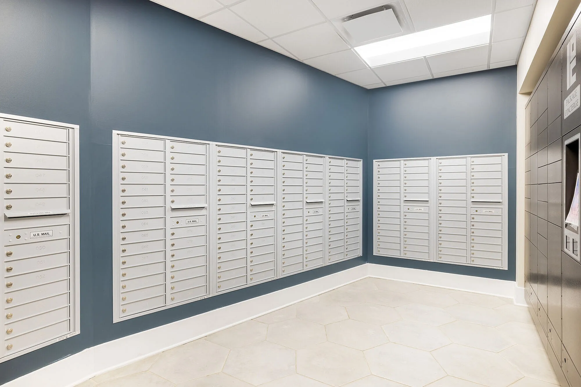 Modern apartment mailroom featuring sleek white mailboxes and stylish blue accent wall, offers convenience and security.