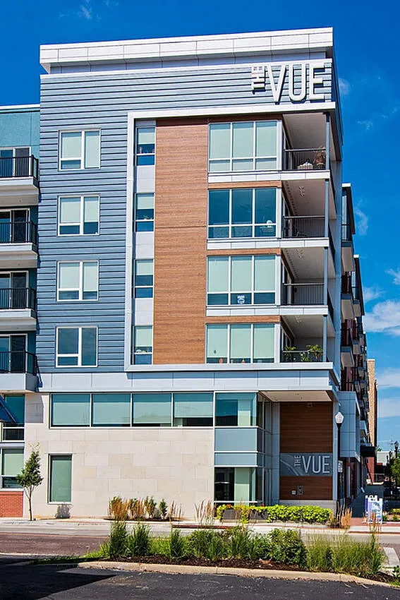 Modern apartment building with sleek design, large windows, and spacious balconies at The Vue, set against a bright blue sky.