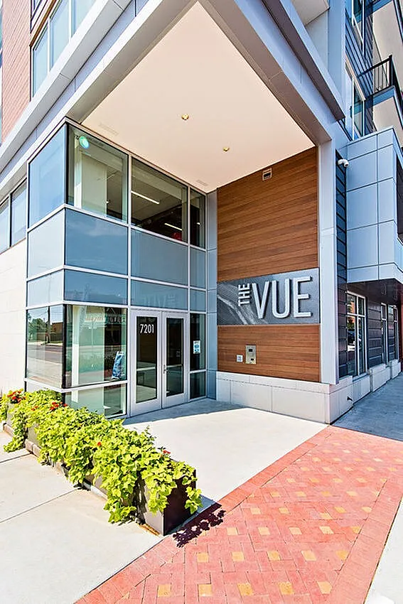 Modern apartment entrance at The Vue with sleek architectural design and vibrant greenery.