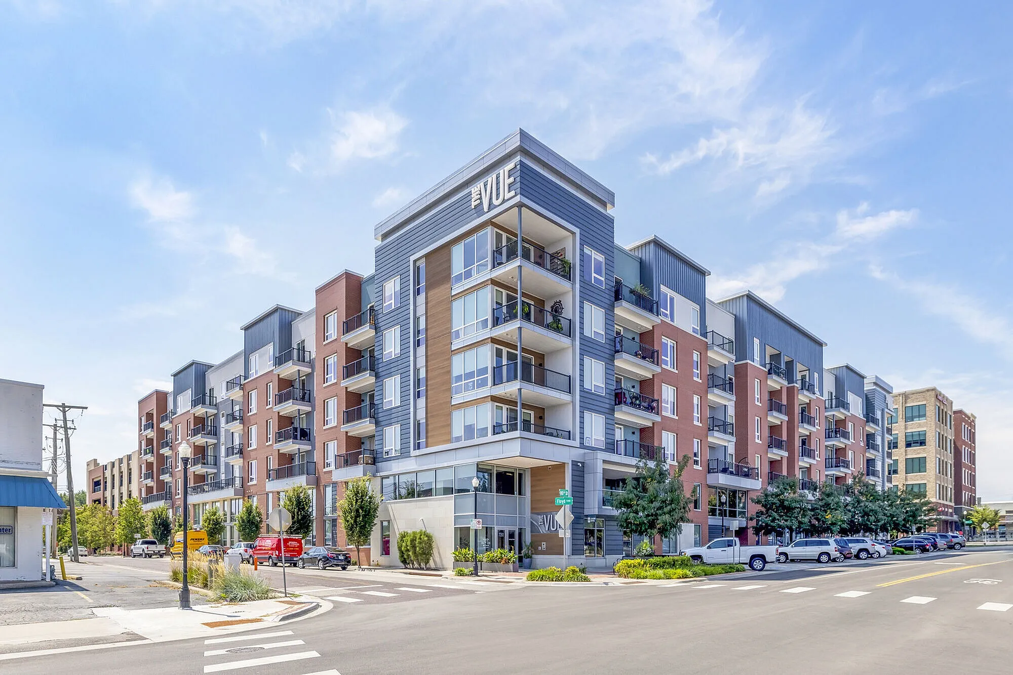 Modern apartment building 'The Vue' with stylish balconies and vibrant urban setting under a clear blue sky.