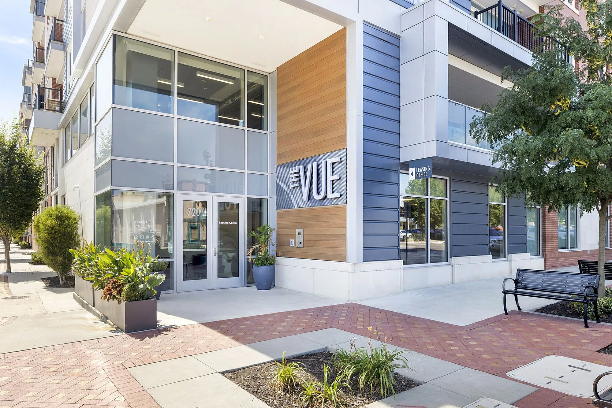 Modern apartment building entrance at The Vue, featuring sleek architectural design with large windows and vibrant greenery.