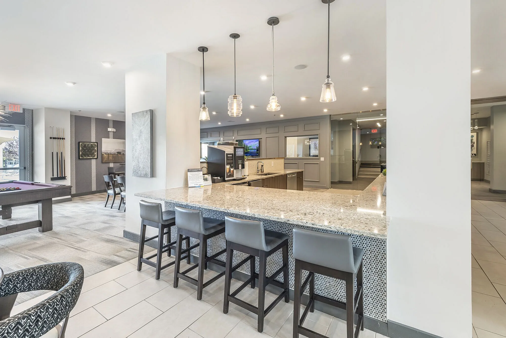 Inviting modern lounge featuring a chic billiards table, elegant bar seating, and contemporary lighting.