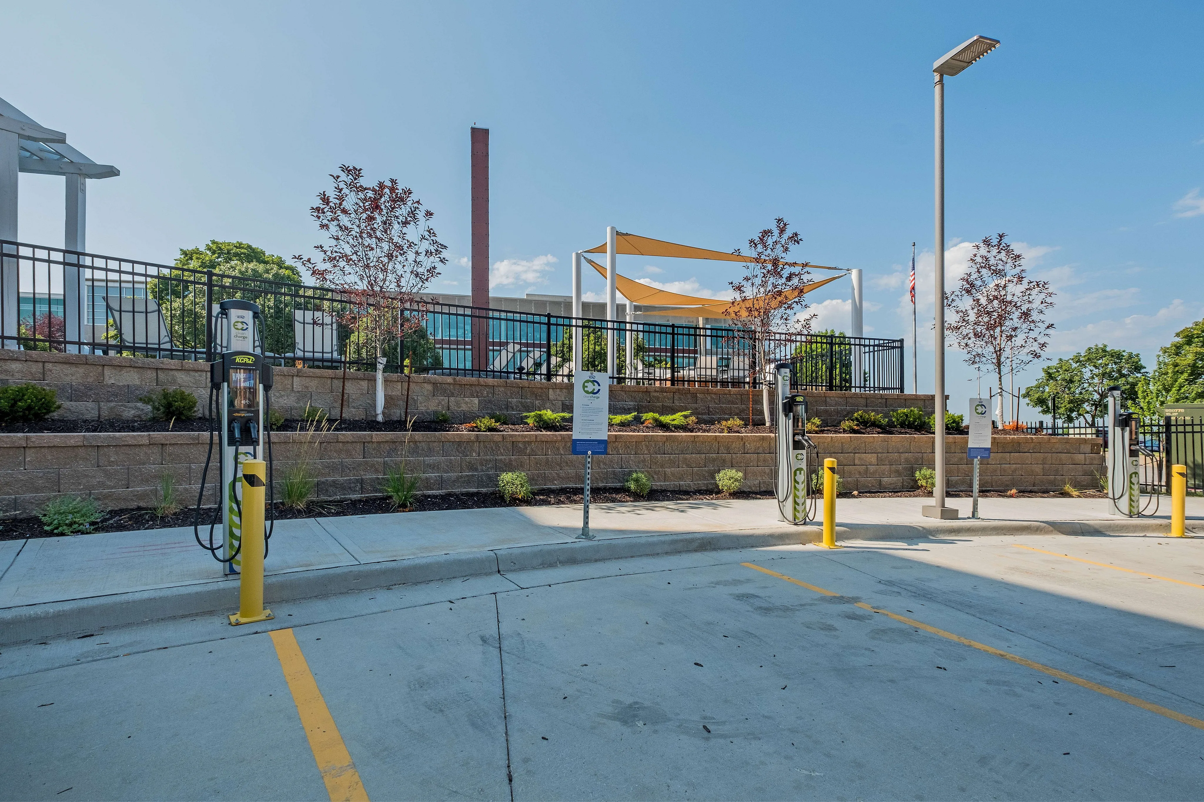 Modern parking area with electric vehicle charging stations and landscaped surroundings, offering sustainable living solutions.