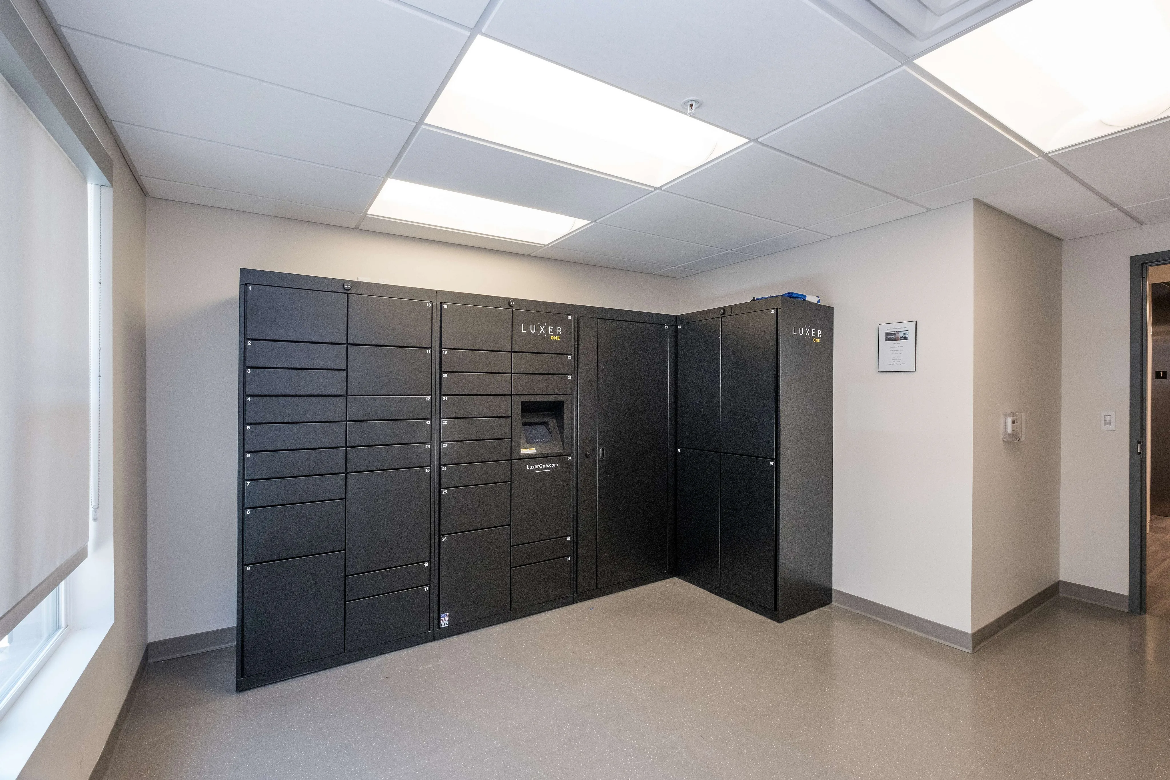 Modern package locker room with sleek black lockers and bright lighting, offering secure parcel storage.