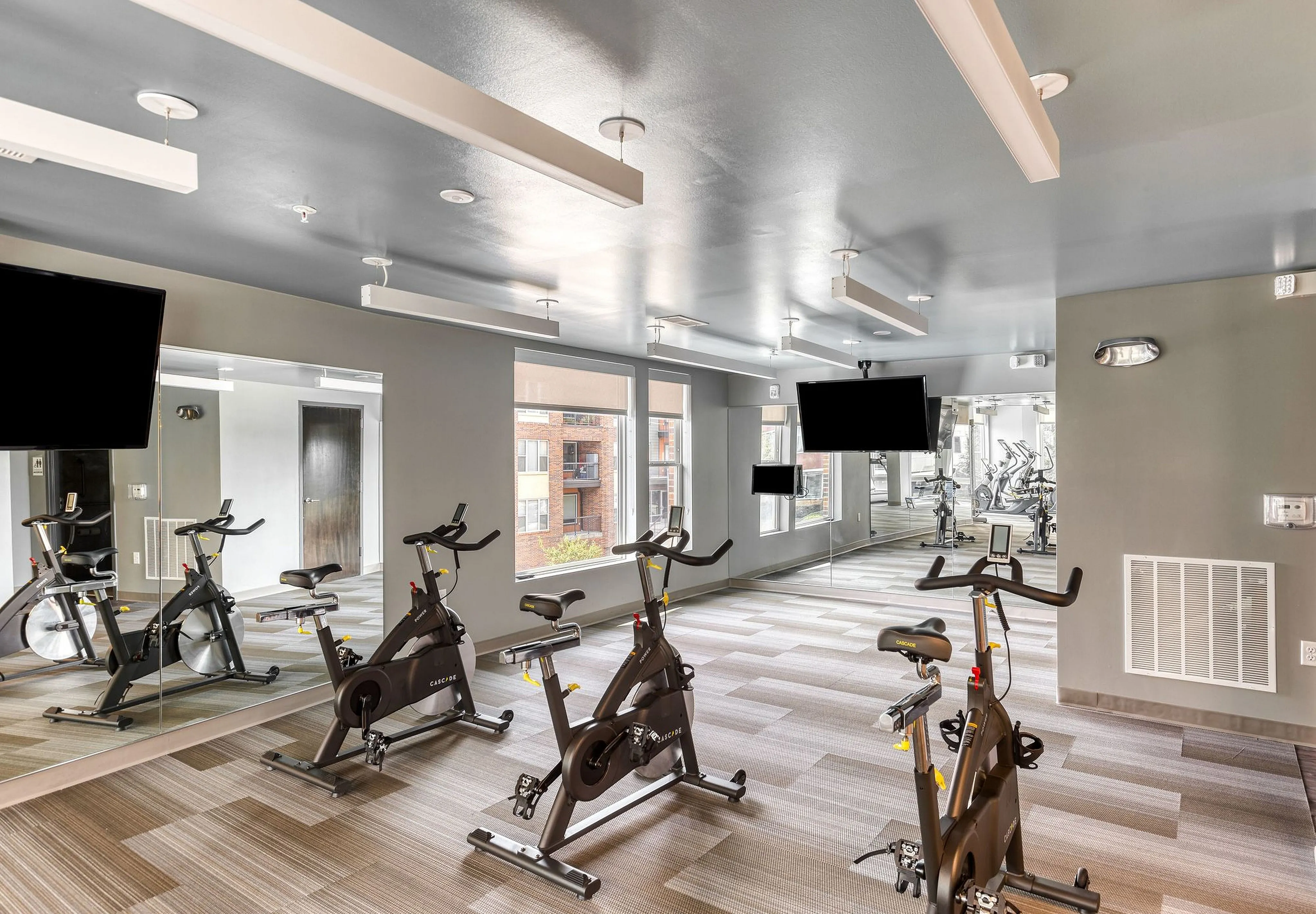 Modern fitness center with state-of-the-art exercise bikes, spacious layout, and wall-mounted TVs.