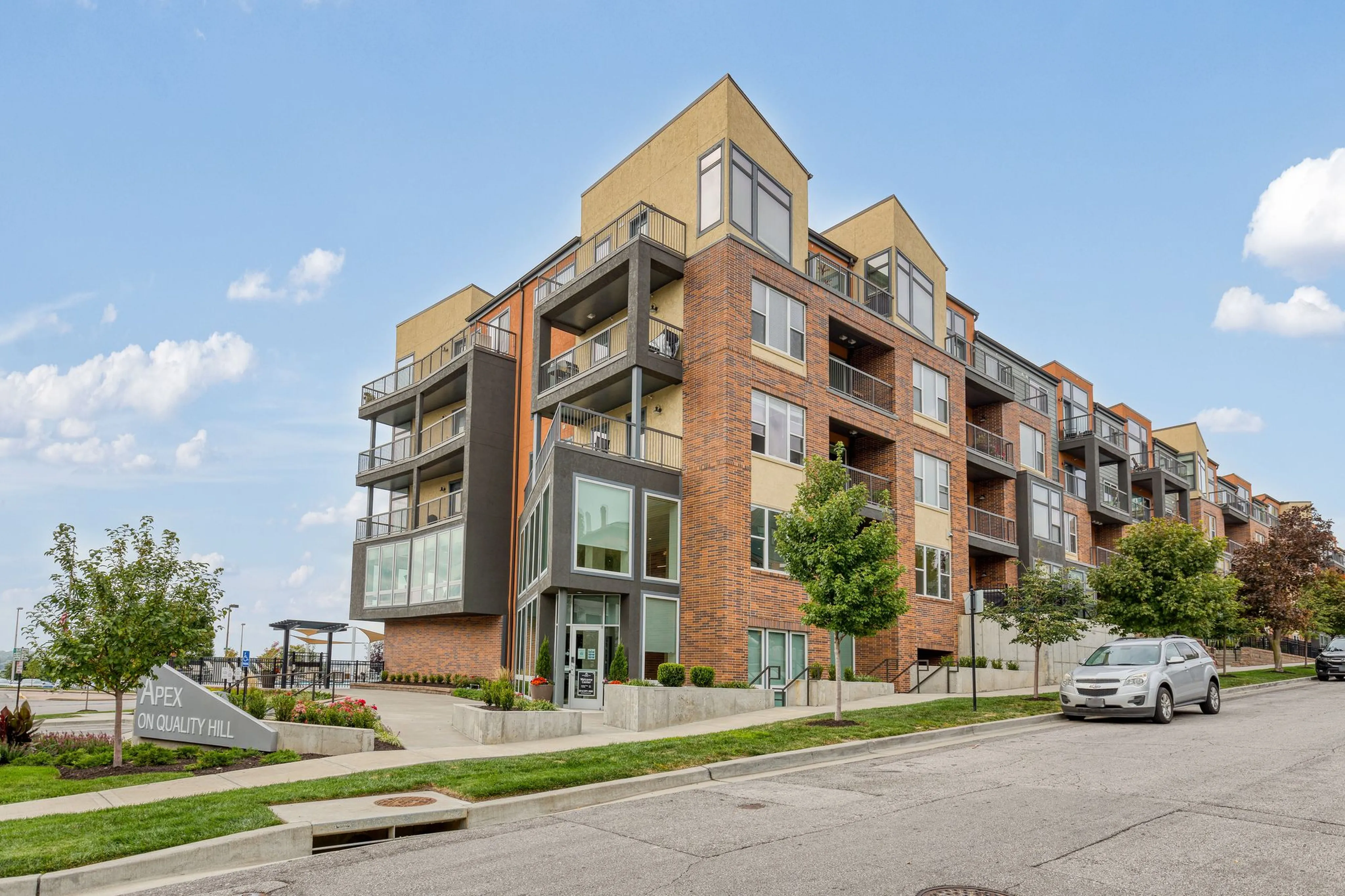 Modern apartment building with stylish balconies and large windows at Apex on Quality Hill, set against a clear blue sky.