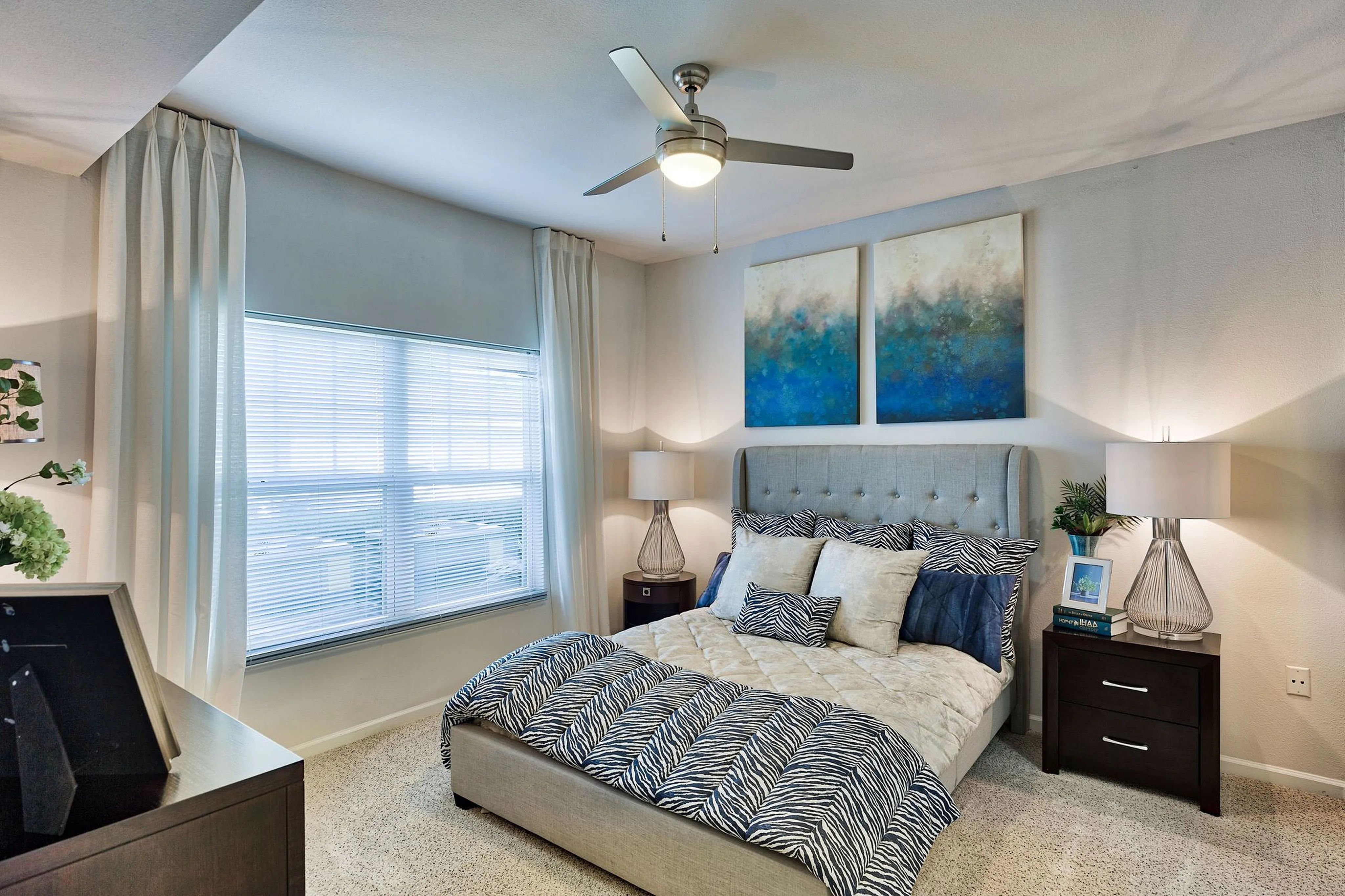 Elegant bedroom with a plush bed, modern decor, and natural light streaming through large windows. Features cozy bedside lamps and stylish wall art for a tranquil atmosphere.