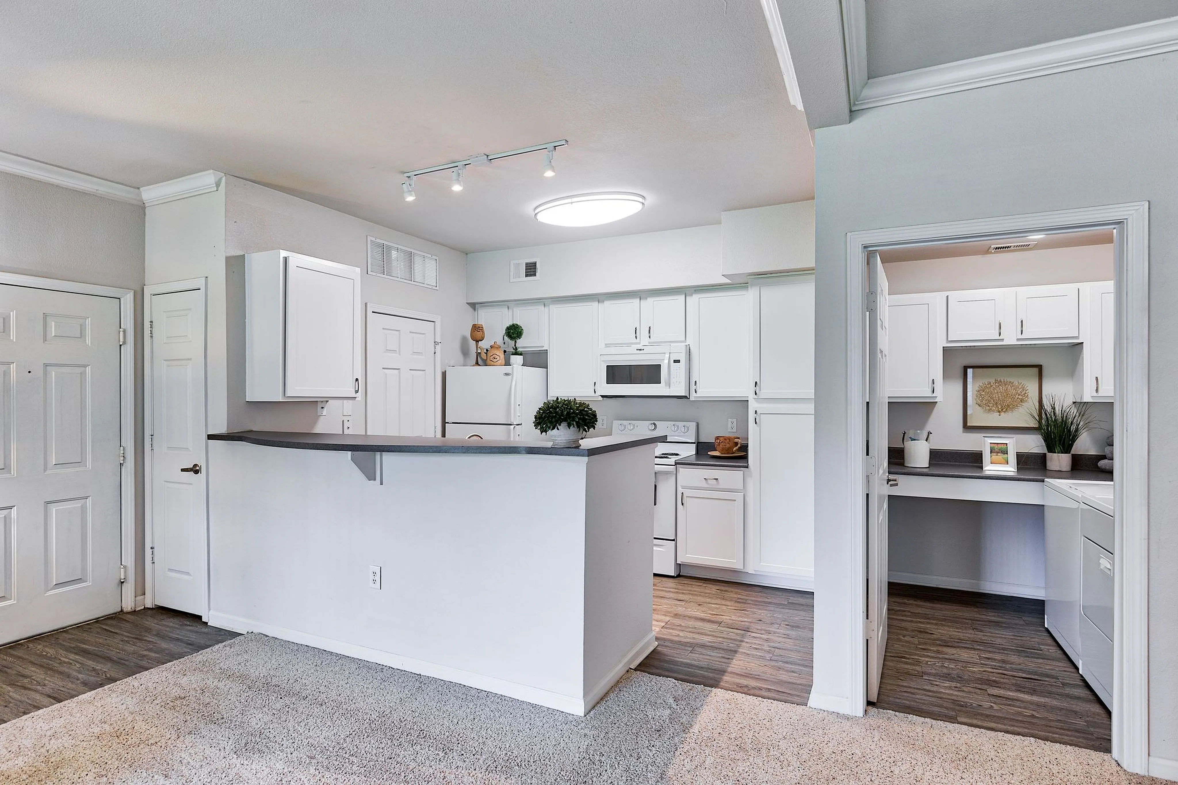 Modern kitchen with sleek white cabinetry, built-in appliances, and charming breakfast bar, ideal for contemporary living.