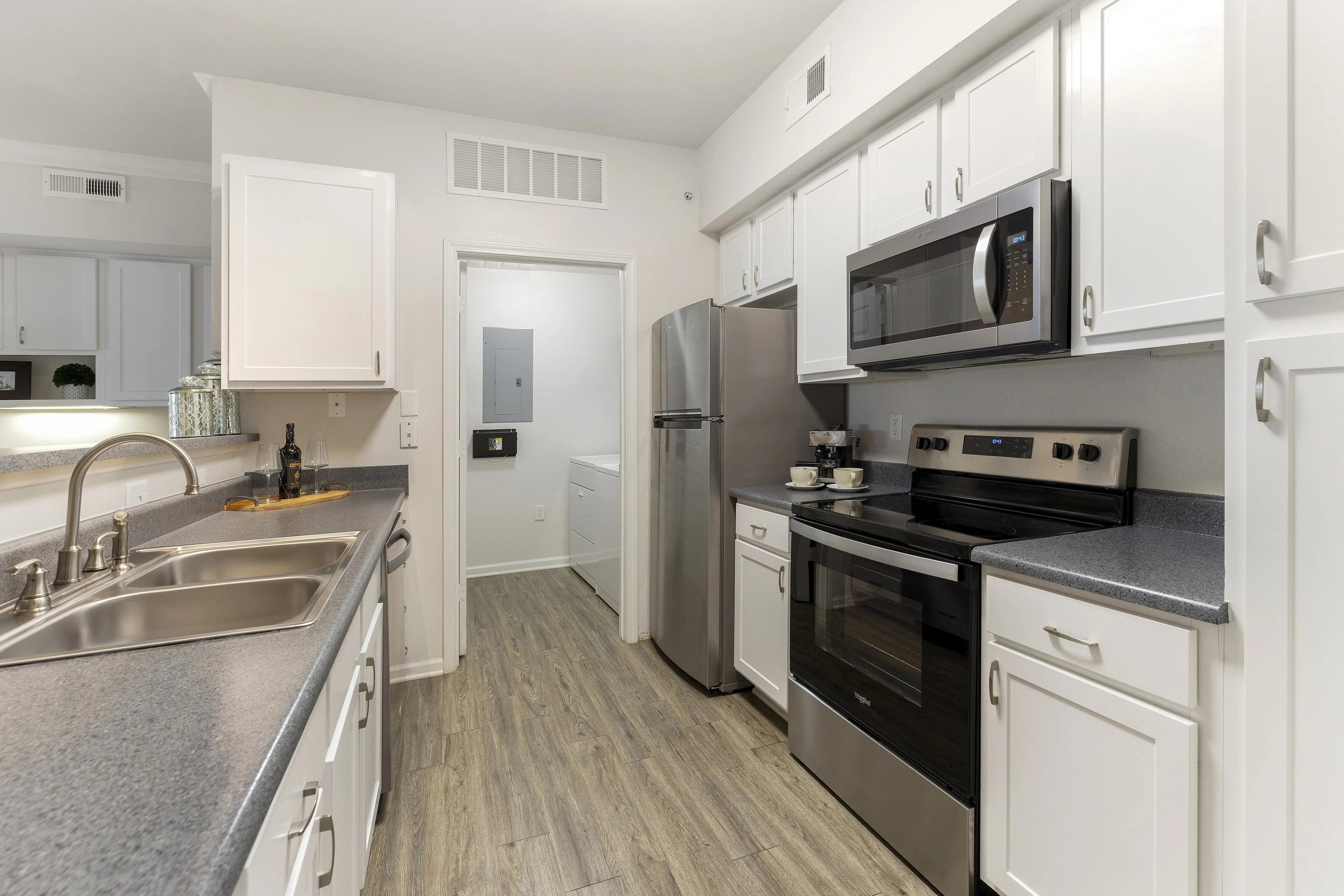 Modern kitchen with sleek stainless-steel appliances, elegant white cabinetry, and stylish wood flooring.