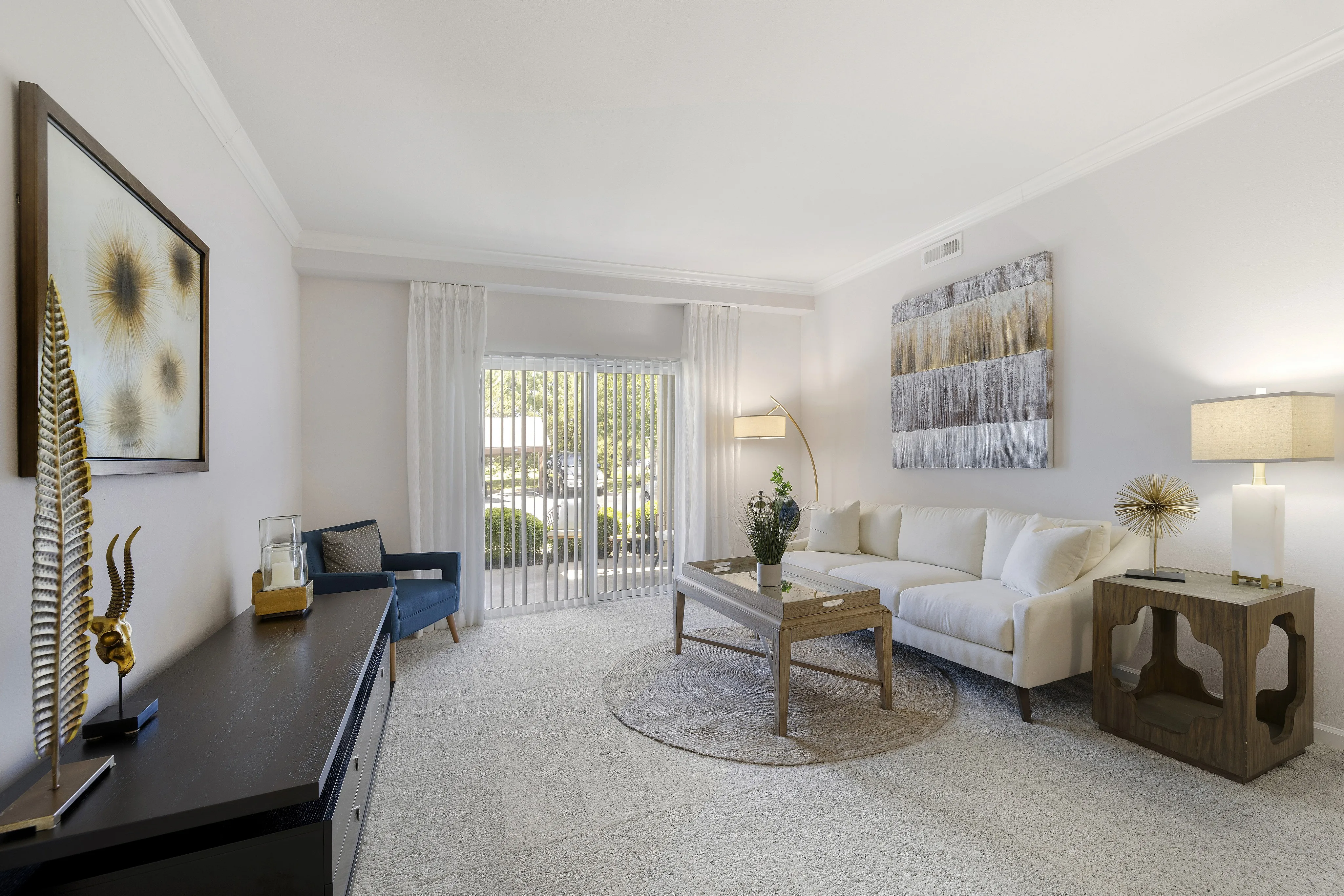 Inviting living room with elegant decor, showcasing a plush white sofa, chic coffee table, and modern artwork, perfectly lit by natural sunlight through large windows.