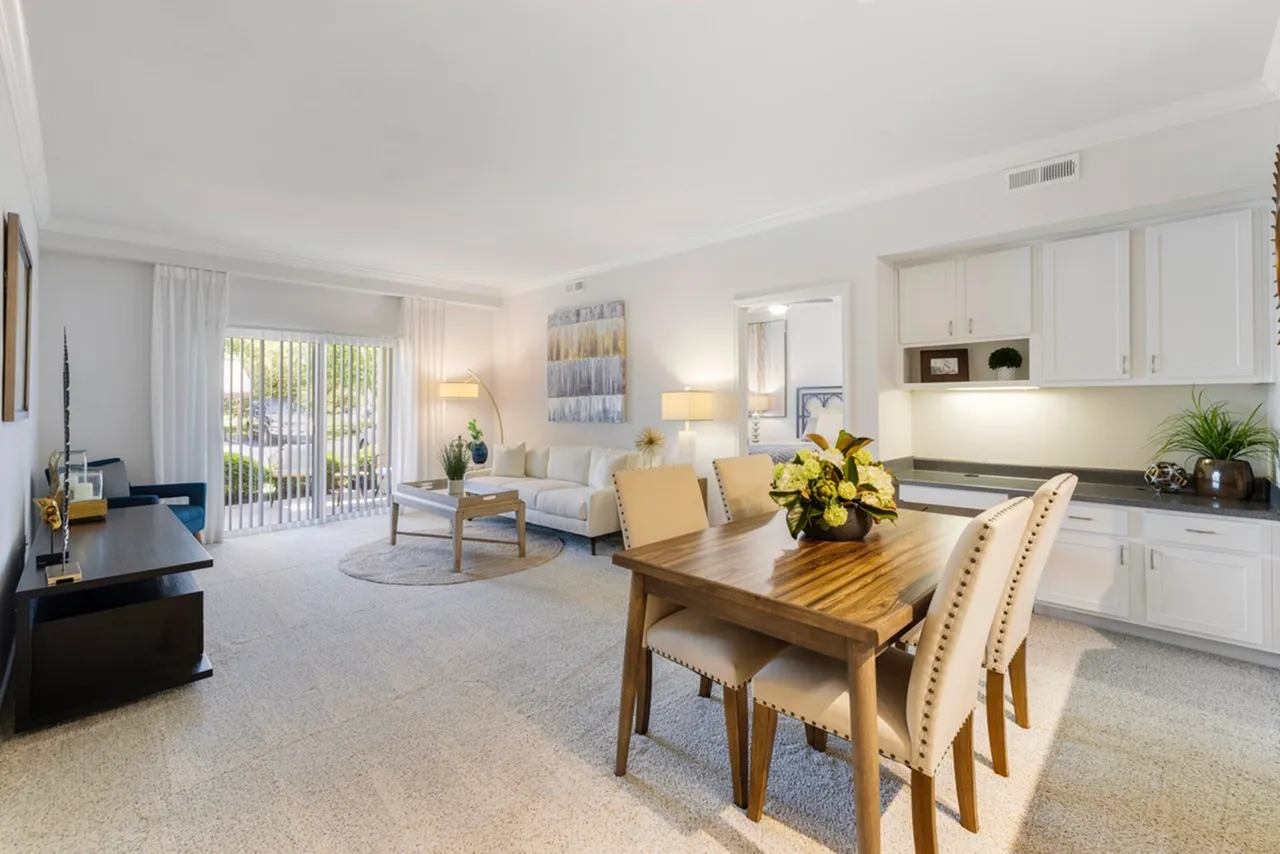 Bright and inviting open-concept living and dining area featuring elegant furnishings, large windows, and a modern kitchen layout.