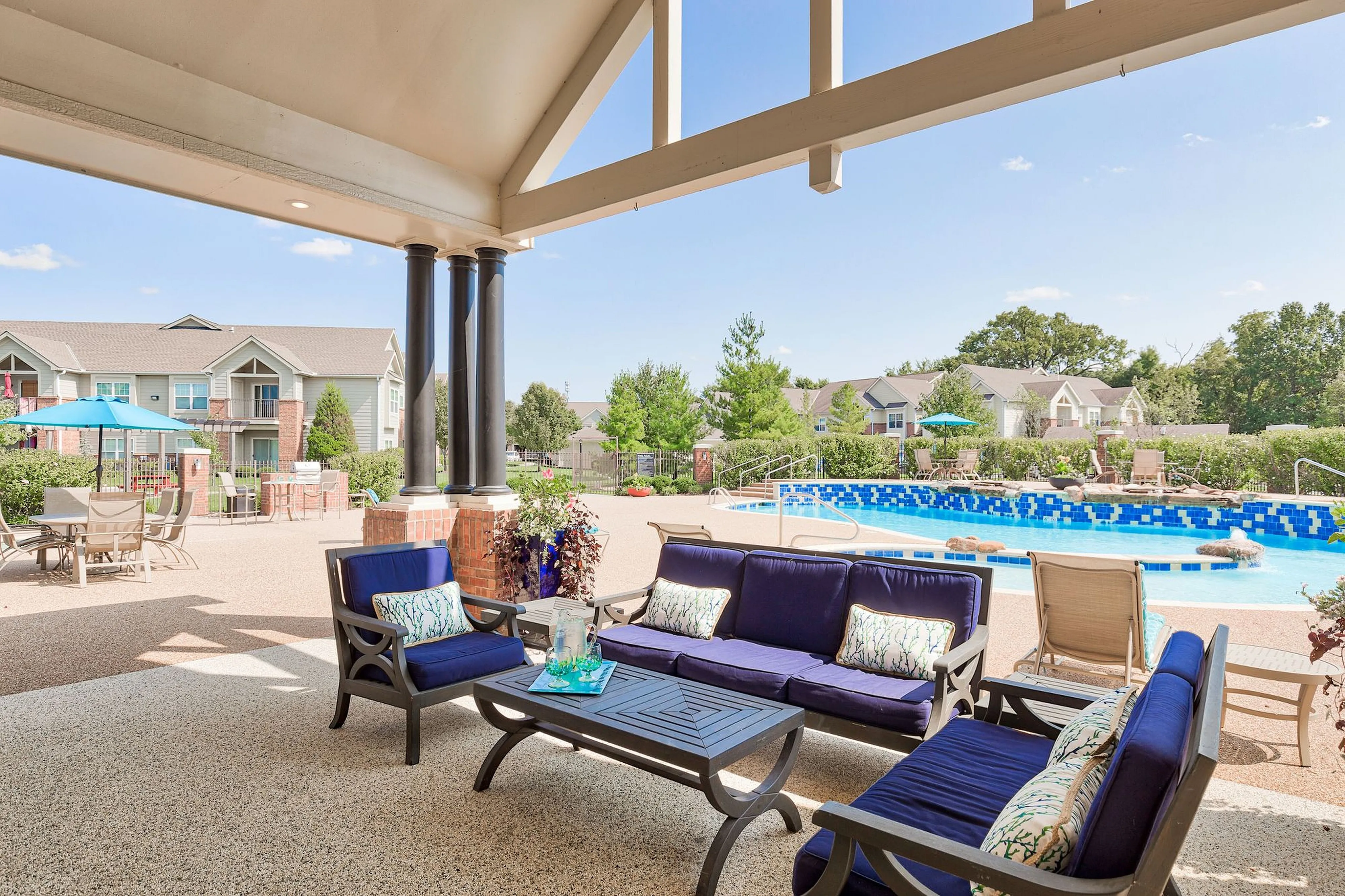 Inviting outdoor lounge with elegant seating overlooks a shimmering pool, perfect for relaxation in a serene apartment complex.