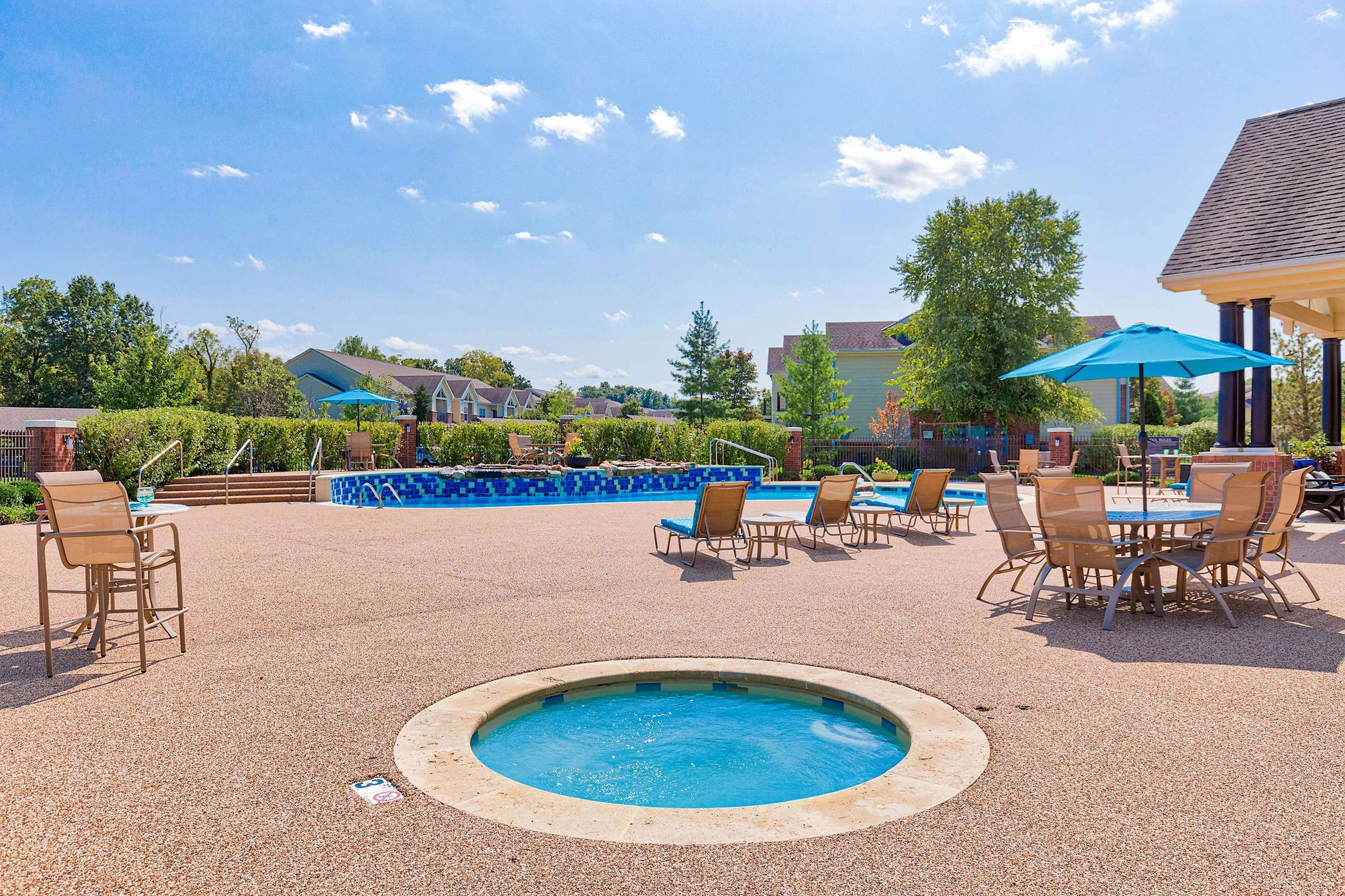 Vibrant outdoor pool area with loungers and umbrellas, surrounded by lush greenery and modern architecture.