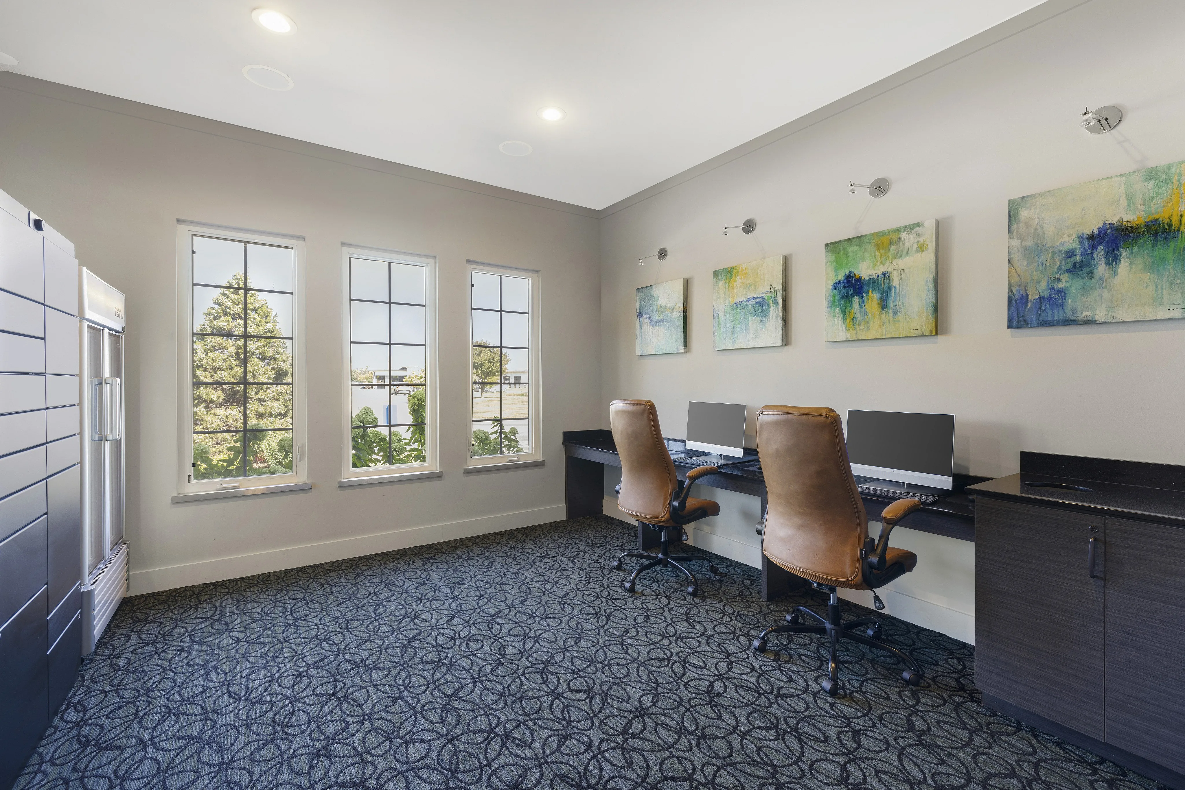 Chic shared workspace with modern decor, featuring dual computer stations and plush leather chairs.