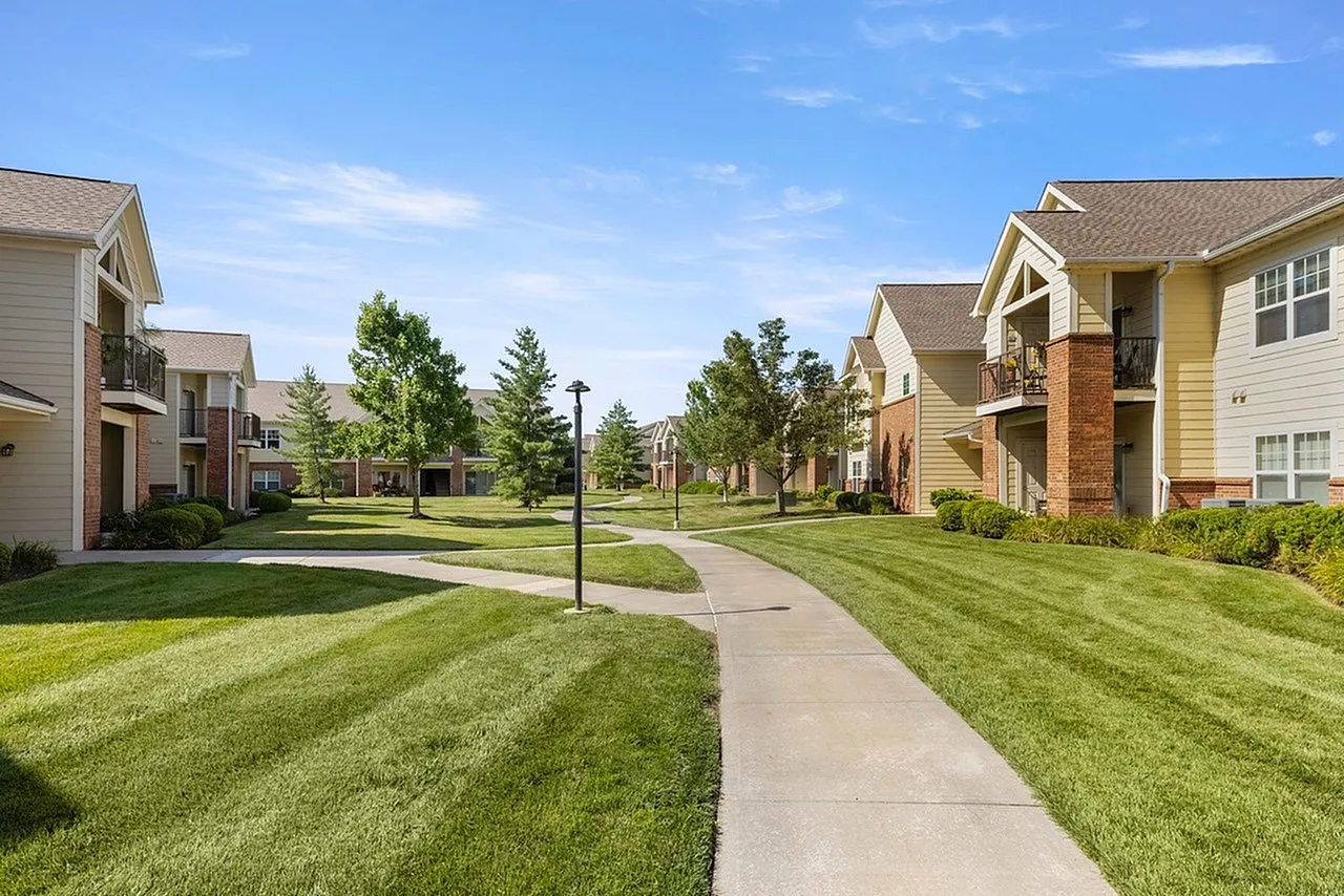 Charming apartment complex with manicured lawns and inviting pathways under a bright blue sky.