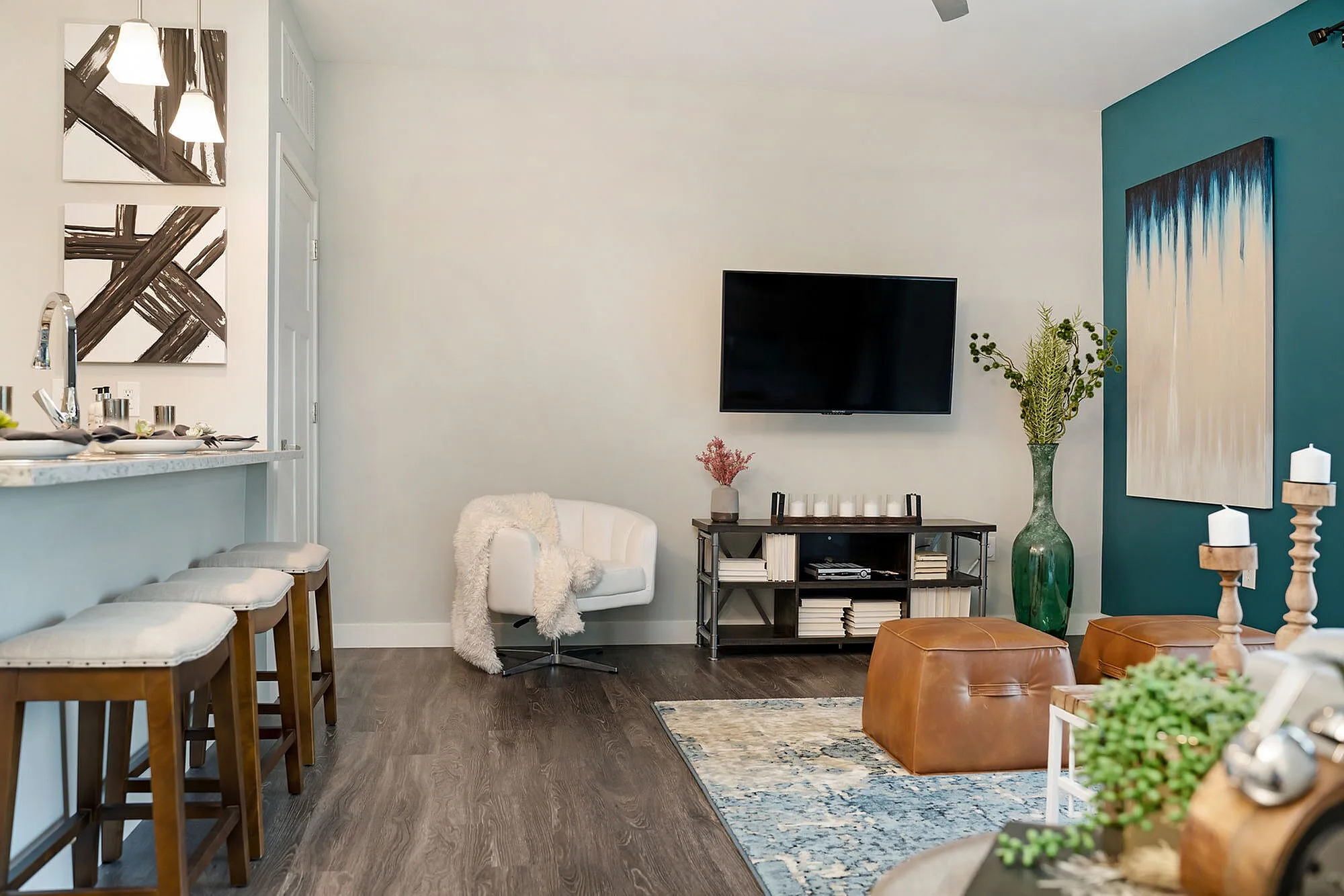 Chic modern living room with elegant decor, featuring a cozy armchair, plush carpet, stylish bar seating, and wall-mounted TV.