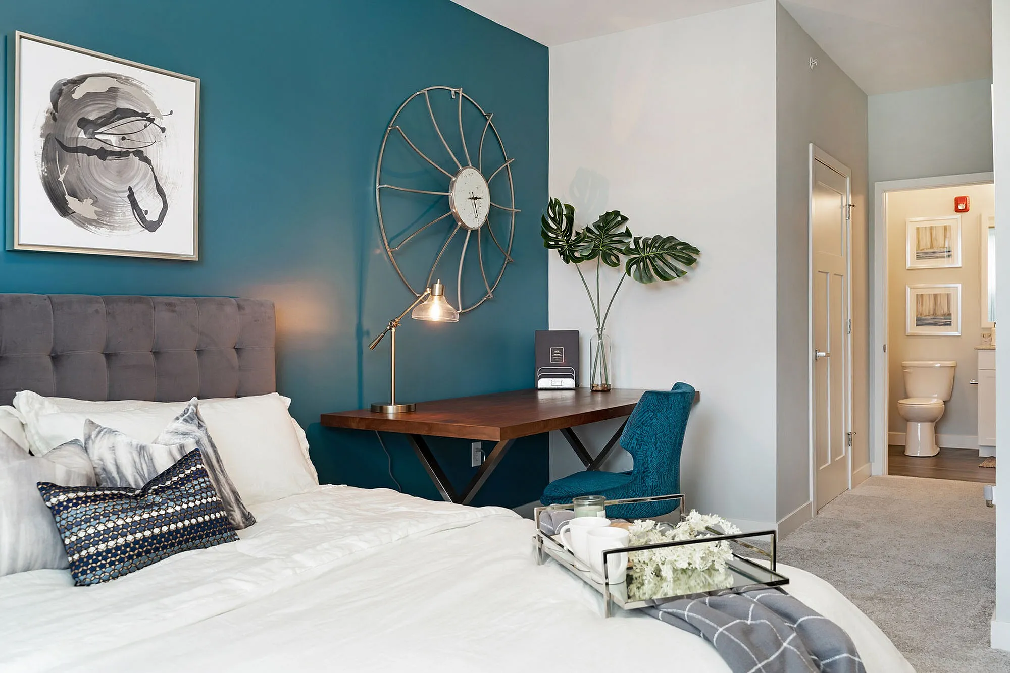 Chic modern bedroom with teal accent wall, stylish desk, and cozy decor enhancing a serene atmosphere.
