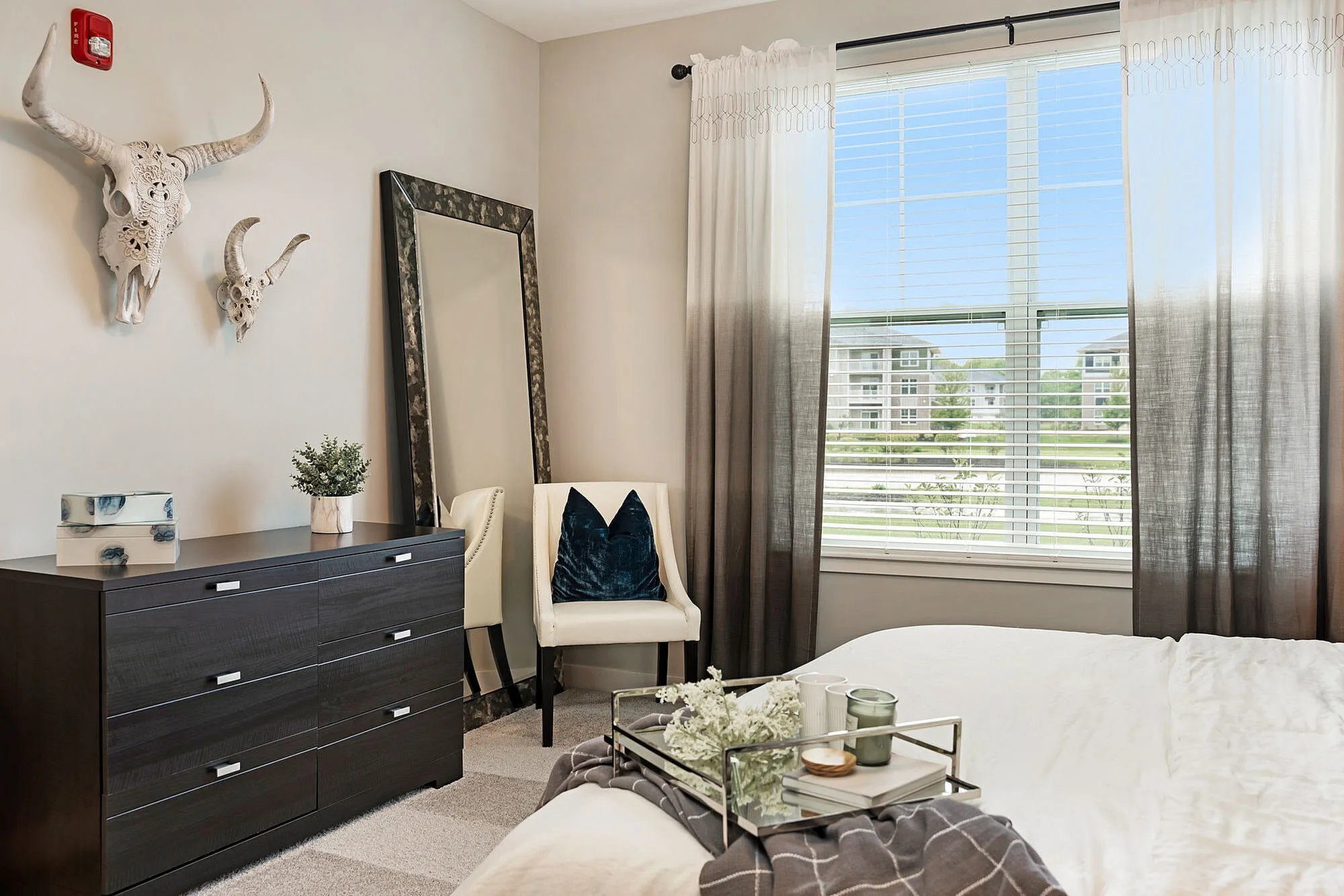 Cozy bedroom with chic decor, featuring contemporary furniture, stylish wall art, and a large window with a scenic view.