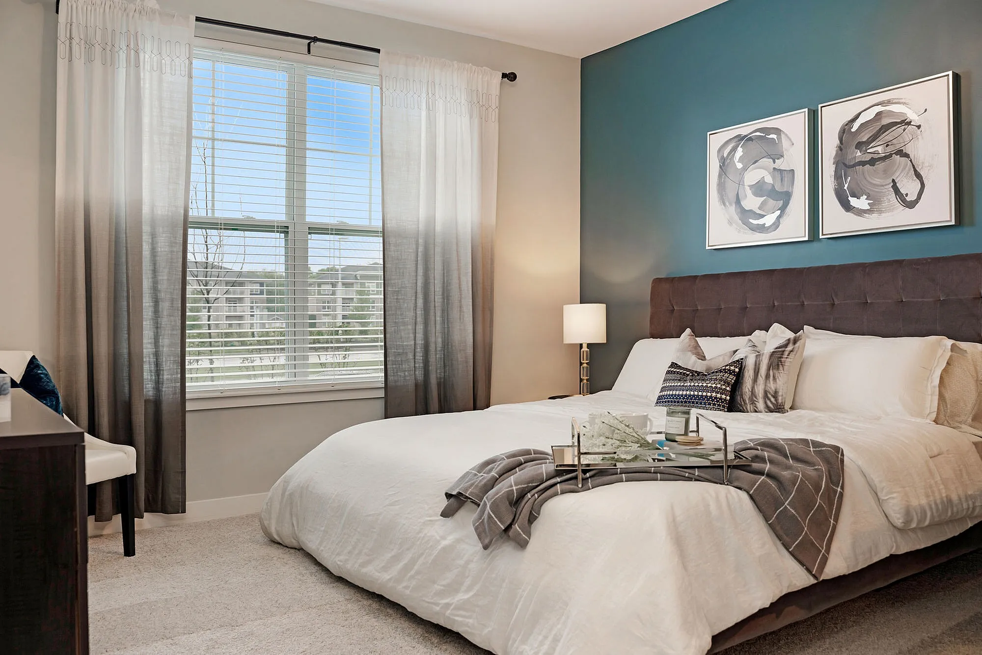 Elegant bedroom with a plush bed, chic decor, and large window with scenic view, offering a serene retreat.