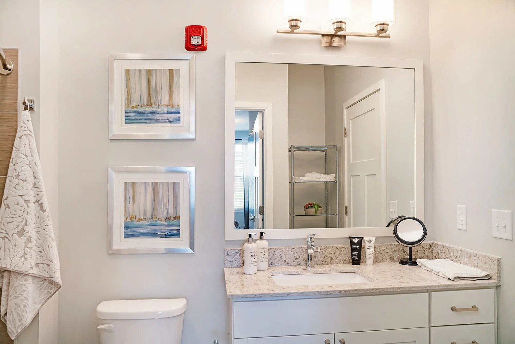 Elegant bathroom with modern granite countertop, framed art, and gleaming mirror offering a bright, inviting space.