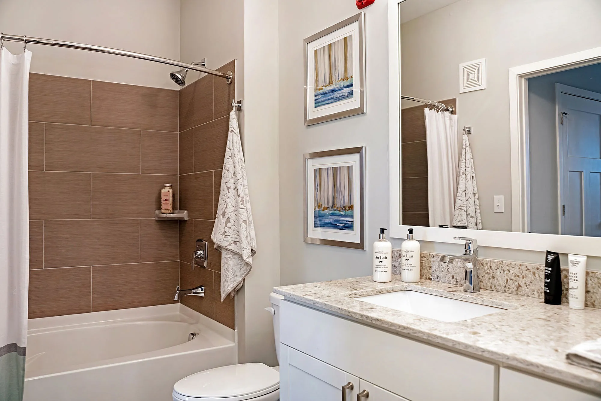 Elegant bathroom with modern granite countertop, chic framed art, and inviting bathtub.
