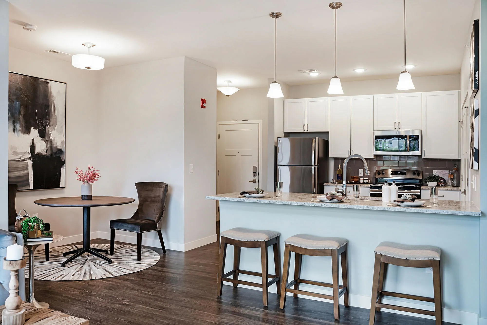 Modern apartment kitchen with sleek appliances, elegant island seating, and a cozy dining nook featuring stylish decor.
