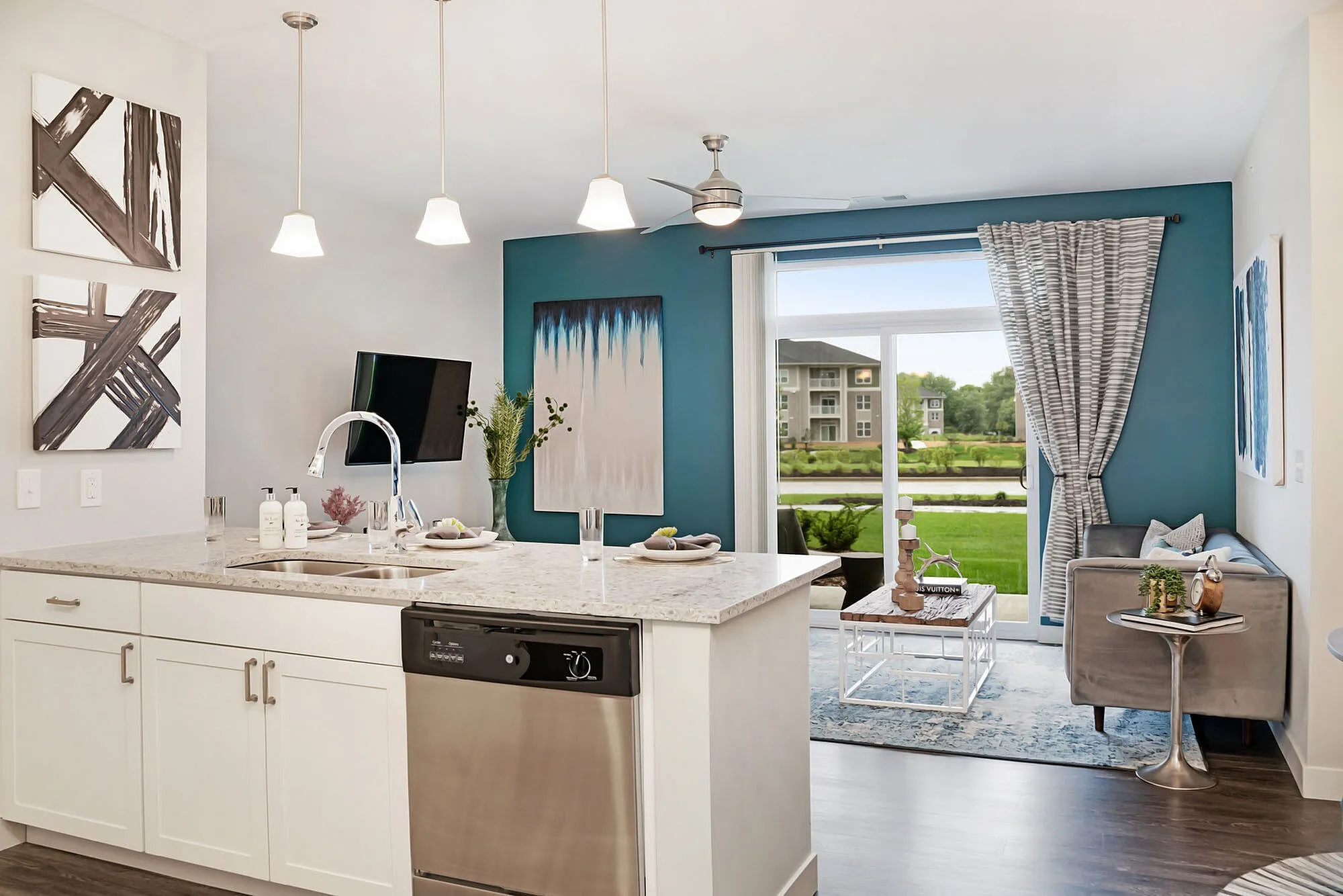 Modern kitchen and living area with sleek design, granite countertops, stylish lighting, and large windows offering a scenic garden view.