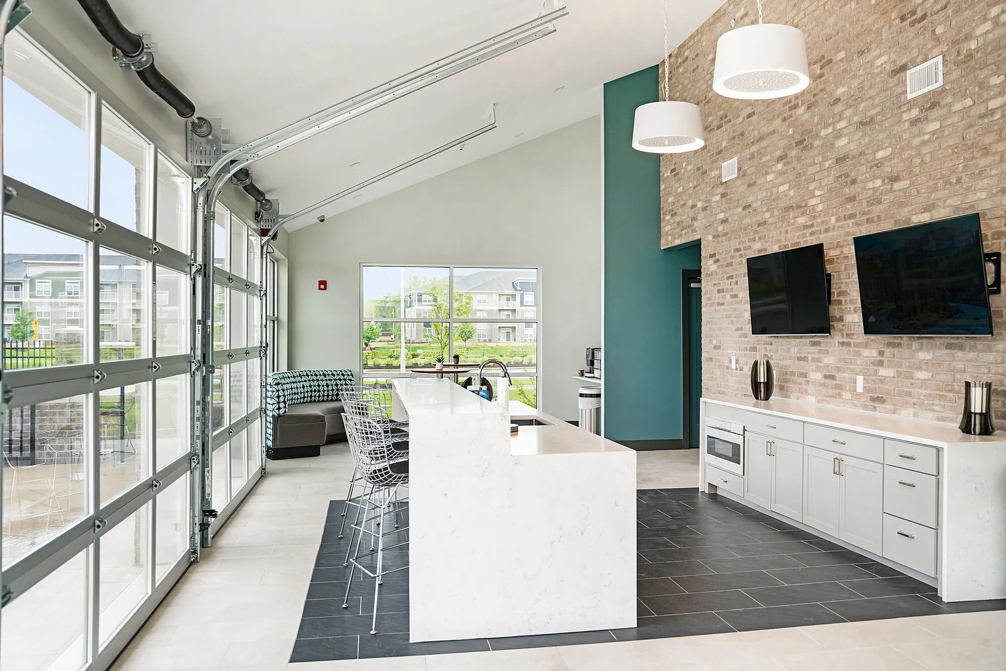 Contemporary open-concept lounge with stylish brick walls, modern kitchen island, and expansive window views in upscale apartment.